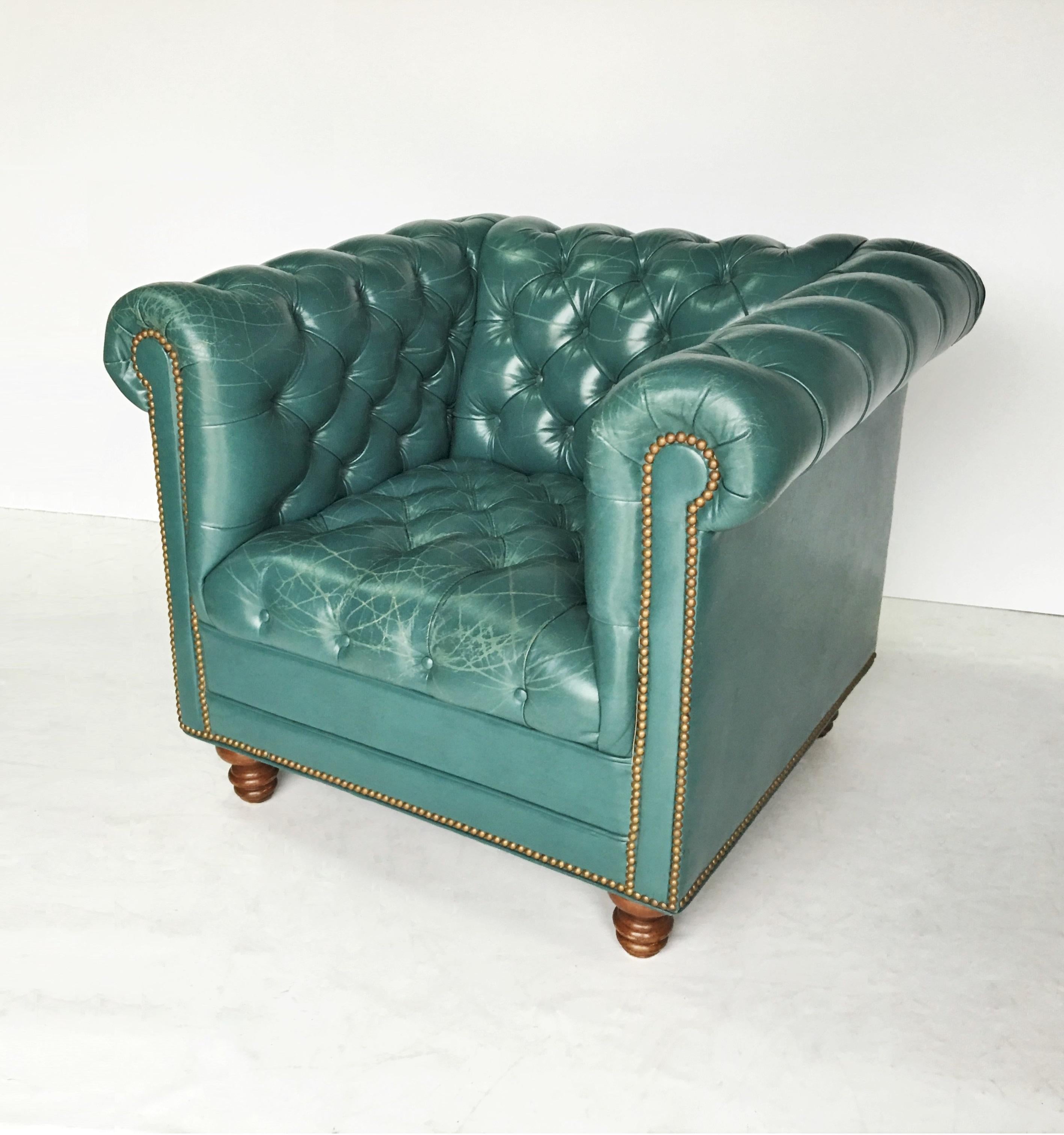 Symbol of elegance and luxury, offered is a pair of vintage Chesterfield club/lounge chairs. Upholstered in a beautifully aged teal, deep tufted buttons and accented with brass nailhead trim. Both chairs raised on solid mahogany bun feet, with