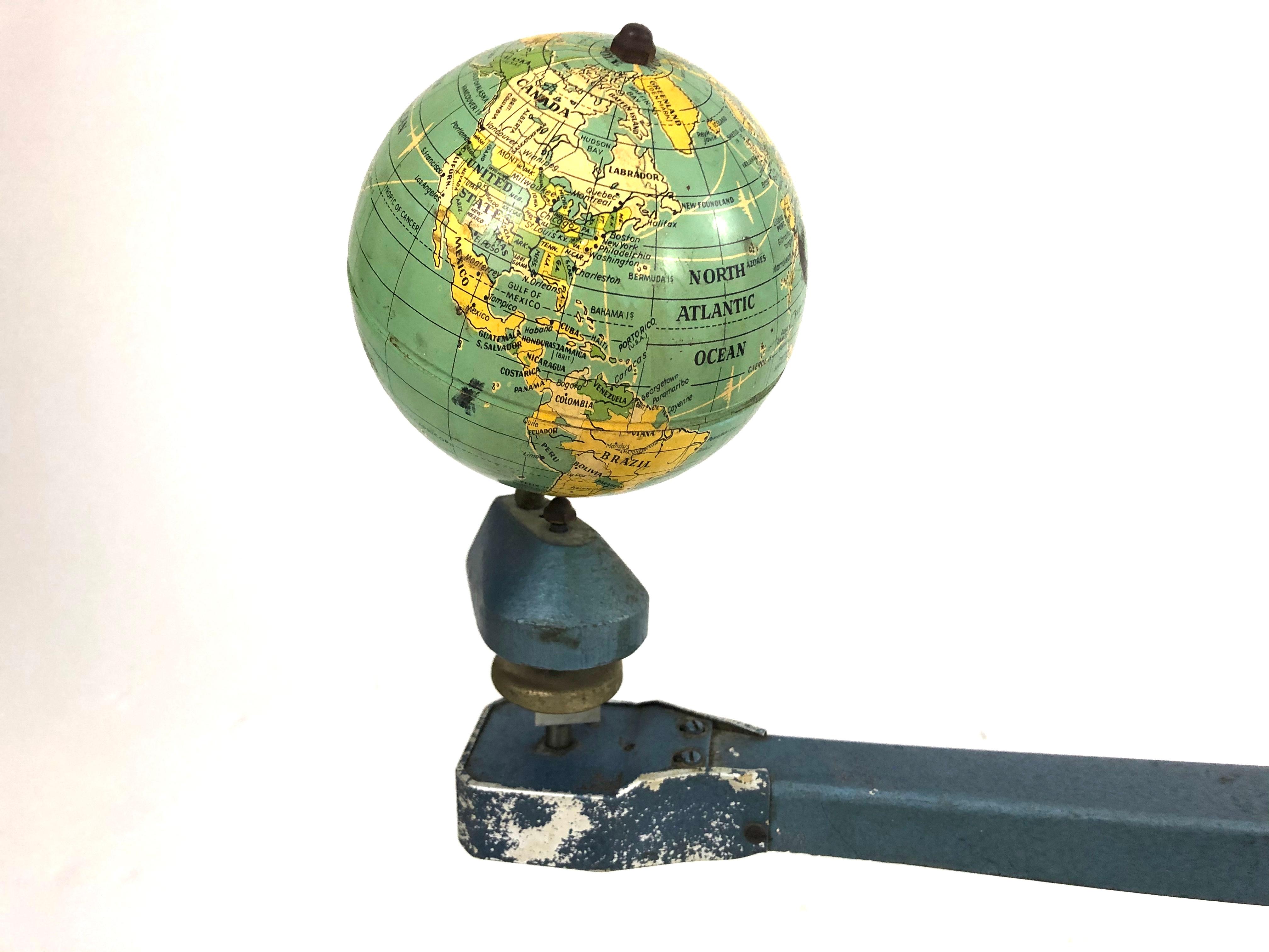 A blue cast metal tellurian which shows how the Earth rotates around the Sun. By winding the hand crank the arm moves in a circle and, simultaneously, the globe spins proportionately, illuminated by a light with visor that represents the Sun.

This