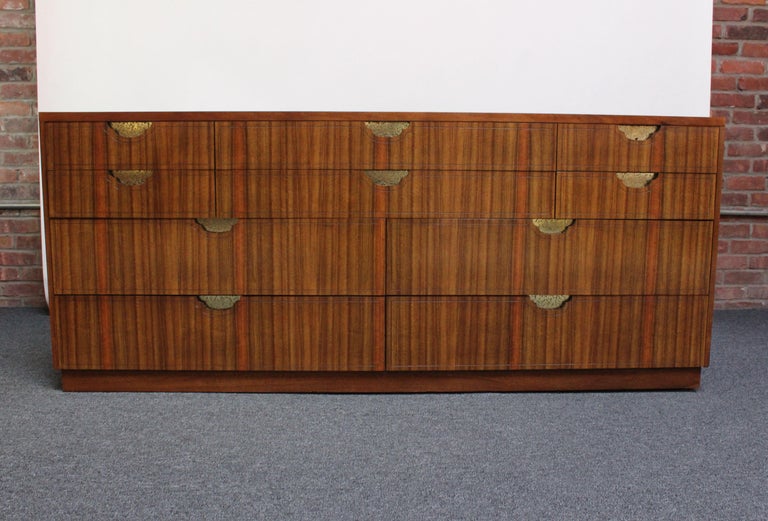 Elegant Baker chest of drawers / dresser in bookmatched black walnut veneer with recessed, hammered and etched brass drawer-pulls and a semi-finished back (ca. 1980,USA).
Ten-drawer configuration with six shallow drawers on top and four more sizable