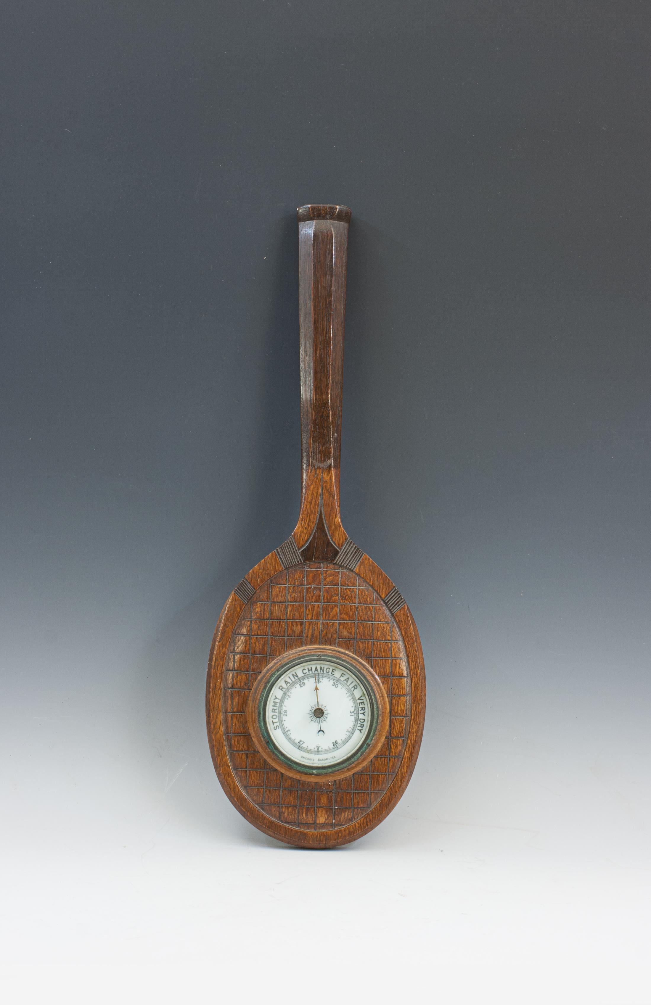 Novelty Barometer, Tennis Racket.
An antique aneroid barometer mounted onto a wooden tennis racquet. The racket has been carved from a piece of oak and is a half model with good shaped handle, concave throat and carved stringing. The barometer