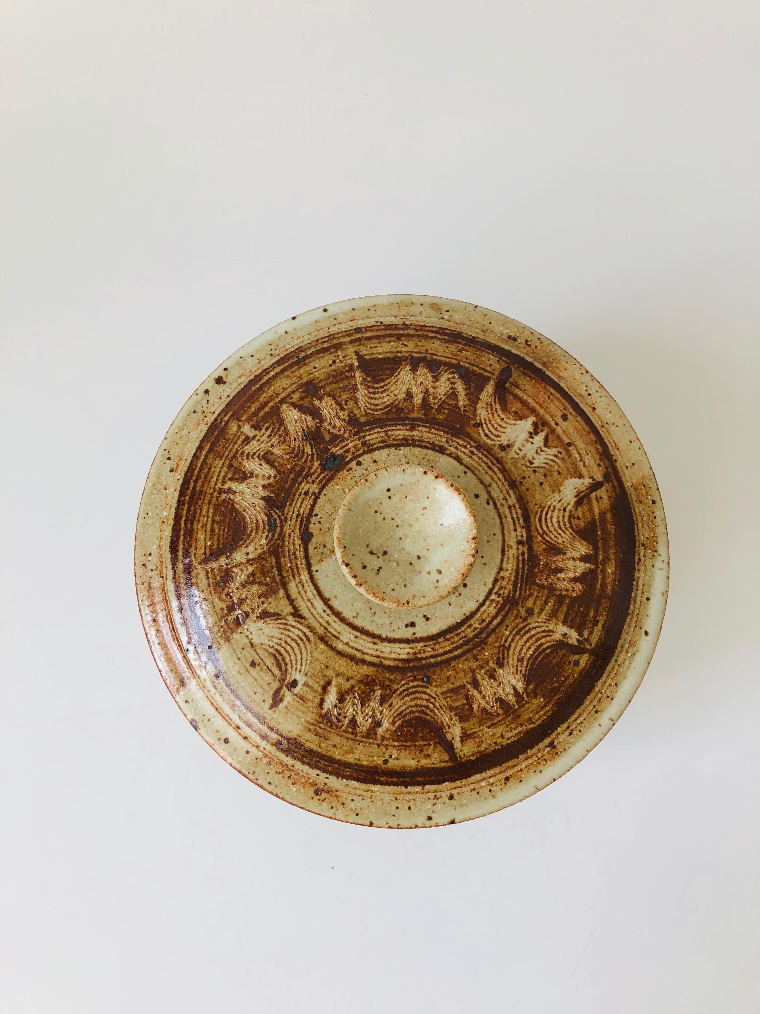Magnifique bol de service à couvercle en poterie Studio vintage. Ce produit présente un motif peint à la main dans des tons de terre. Belle taille, parfaite pour servir une variété de plats. Signé sur la base par le fabricant et daté de 1980.
  