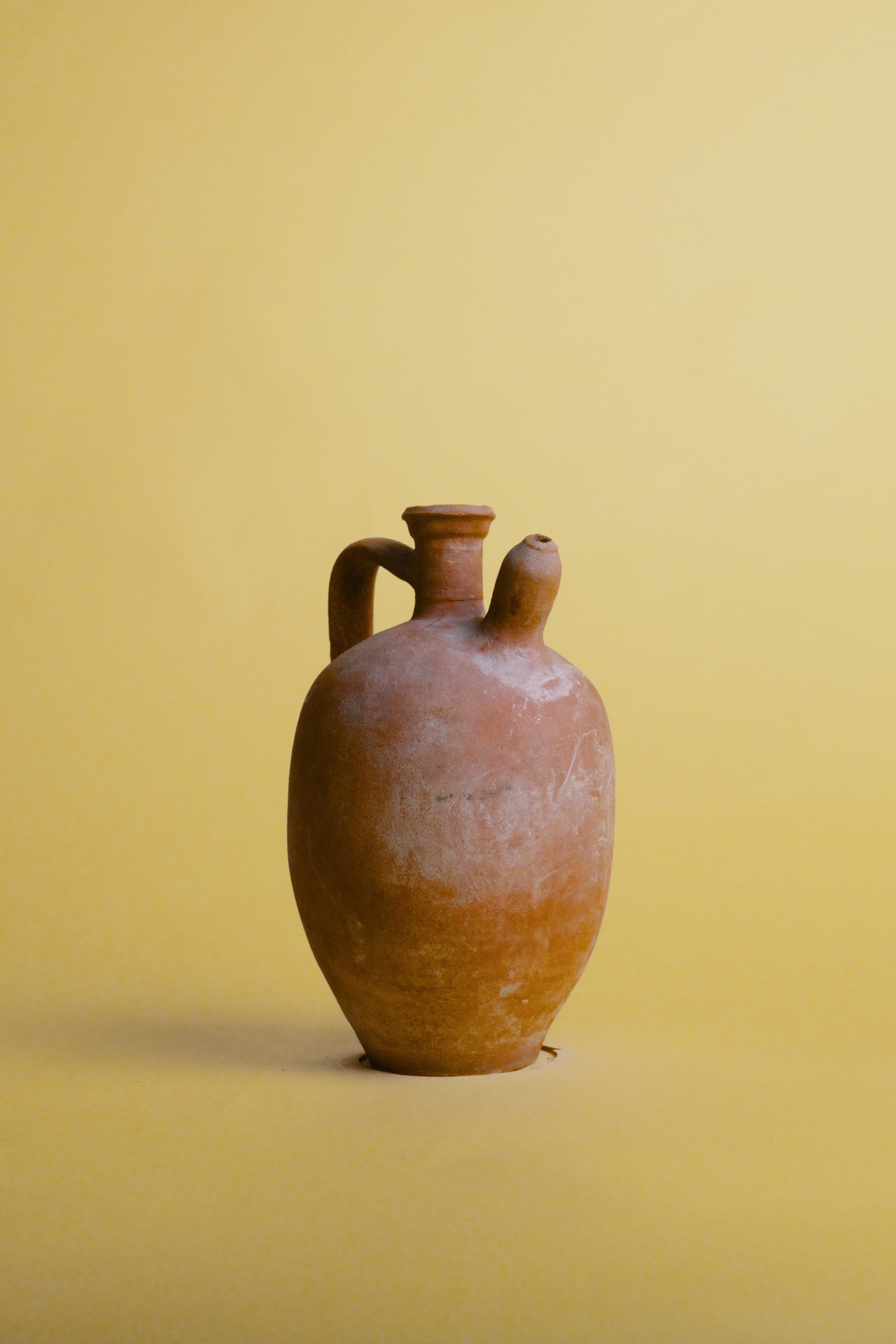 Enhance your space with this vintage terracotta oil jug, featuring a distinctive side spout and a rich, earthy patina that speaks to its Mediterranean origins. Handcrafted using traditional pottery techniques, this rustic vessel reflects the