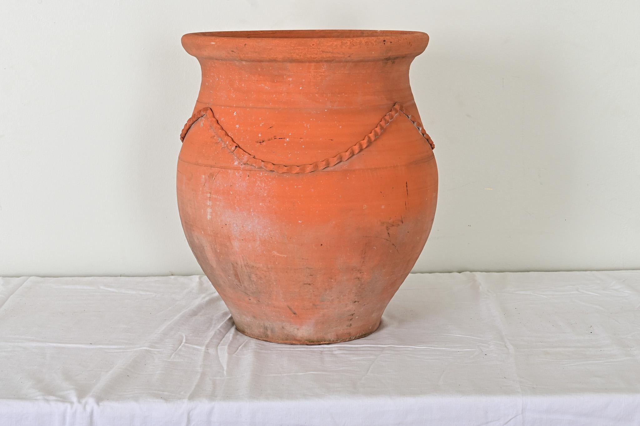 Preciosa jardinera de terracota procedente de Francia, siglo XX. Una fina cinta sobre los hombros de la vasija da un toque de delicadeza a su forma bulbosa. Cómodo orificio de drenaje en la parte inferior para utilizarlo en el patio o emparejado con