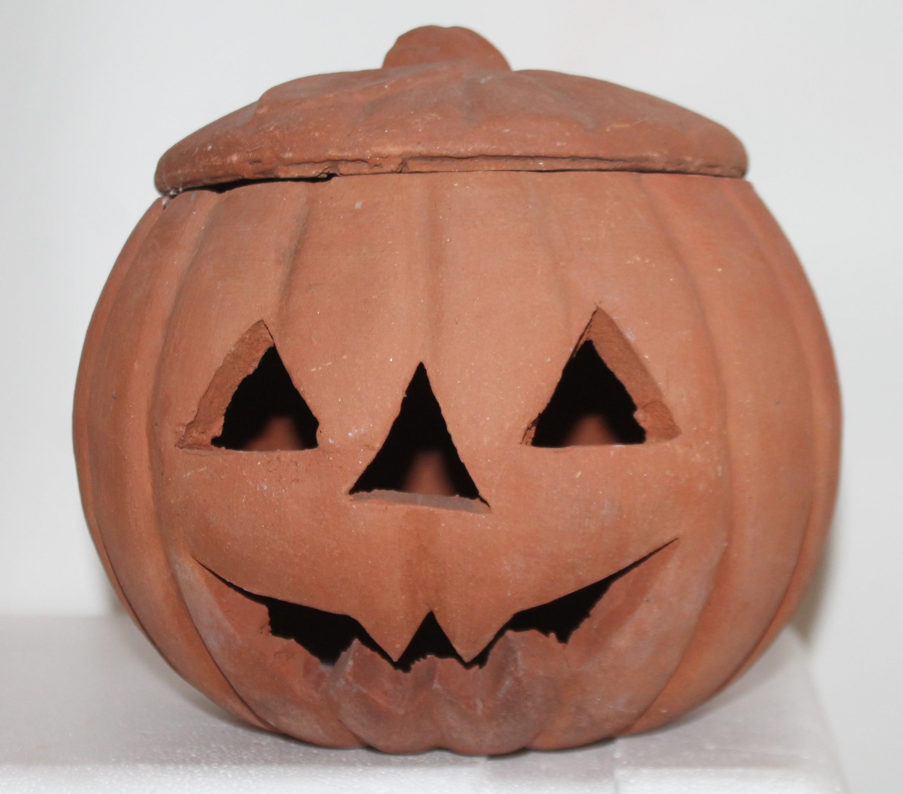 This fun pottery terracotta jack o lantern looks like it was a outdoor porch ornament. Nice wear and worn patina. The inside lip has minor flakes or tiny chips. It is the size of a full size pumpkin.