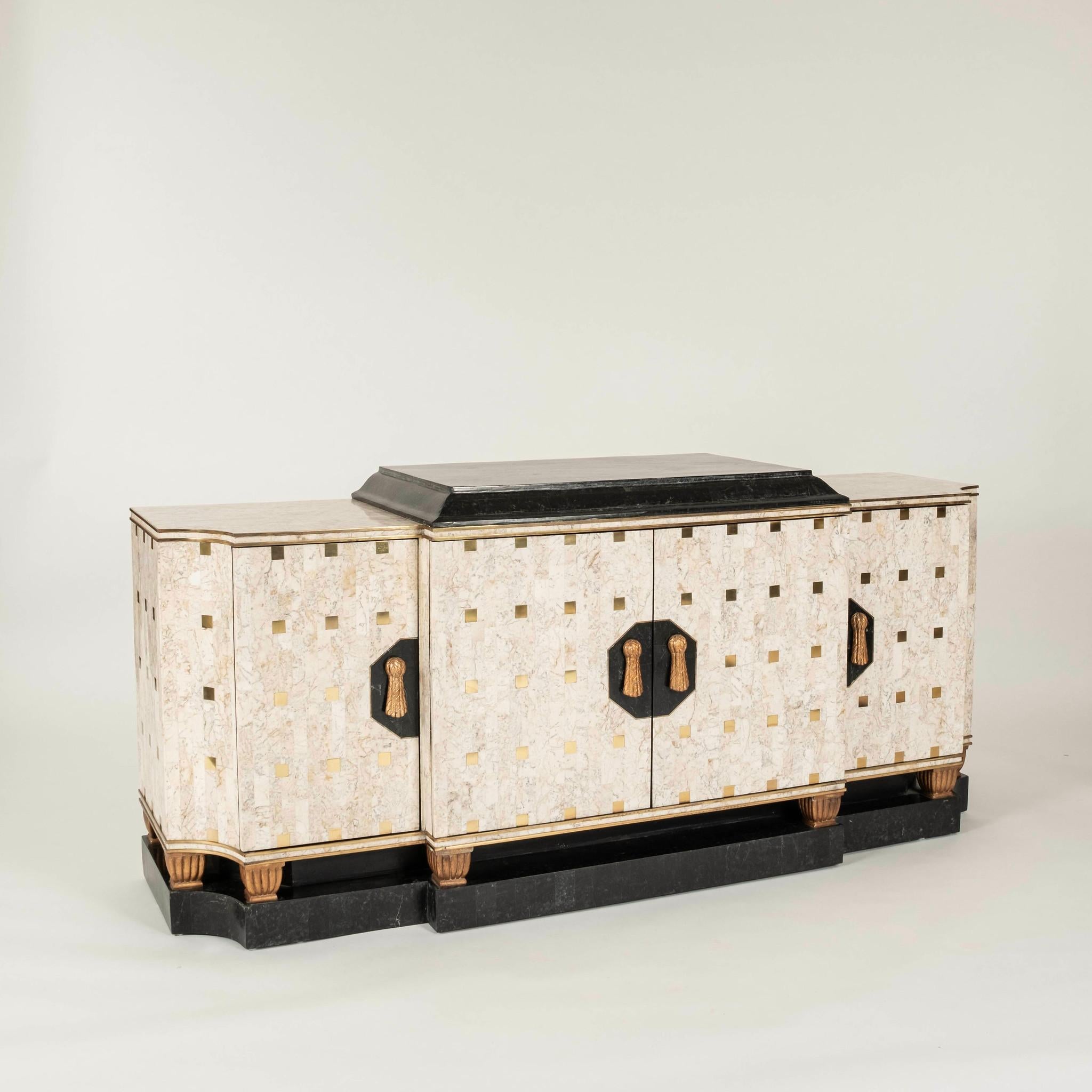 Stylized tessellated marble four door cabinet featuring raised plinth top, giltwood detailing, brass inlay with tassel hardware.