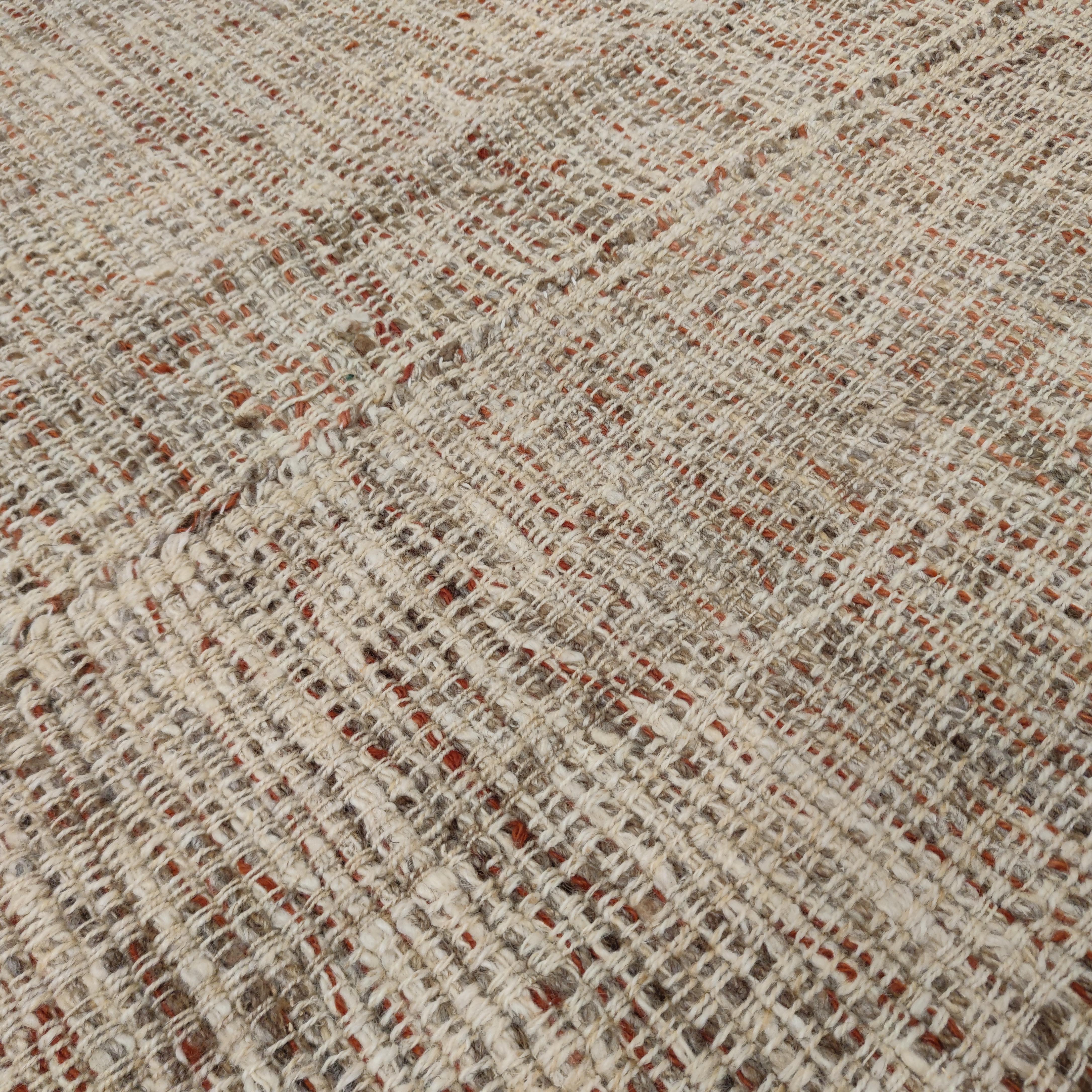 A rare and unusual room-size wool flat-weave, most probably commissioned for the European market during the post-war years, distinguished by a textural interlace of wool threads in neutral shades alternated to touches of burgundy red wool. The end
