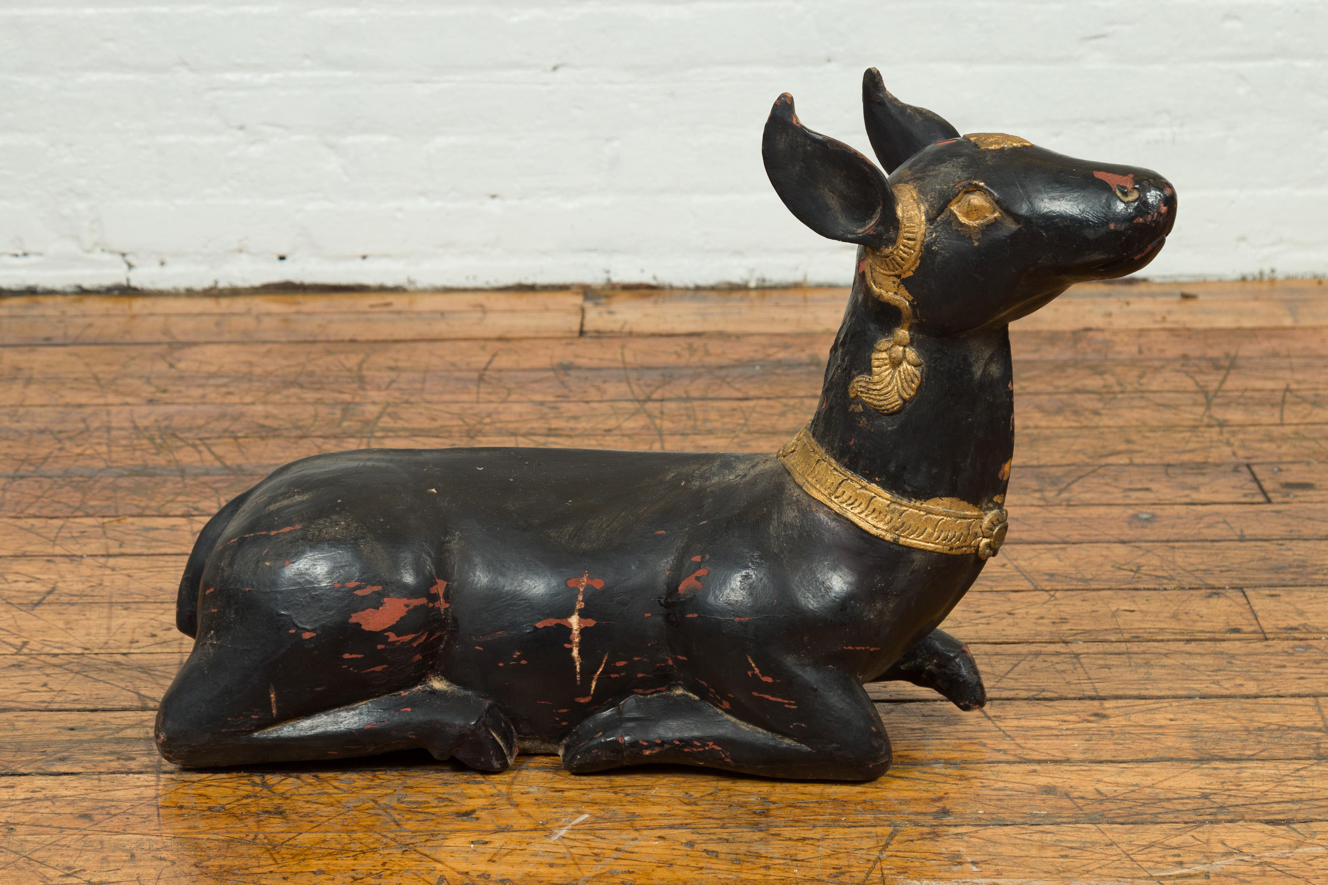 A vintage Thai black lacquered goat sculpture from the mid-20th century, with gold highlights and ornate motifs. Crafted in Thailand during the midcentury period, this wooden goat sculpture features a black lacquered body showing good signs of