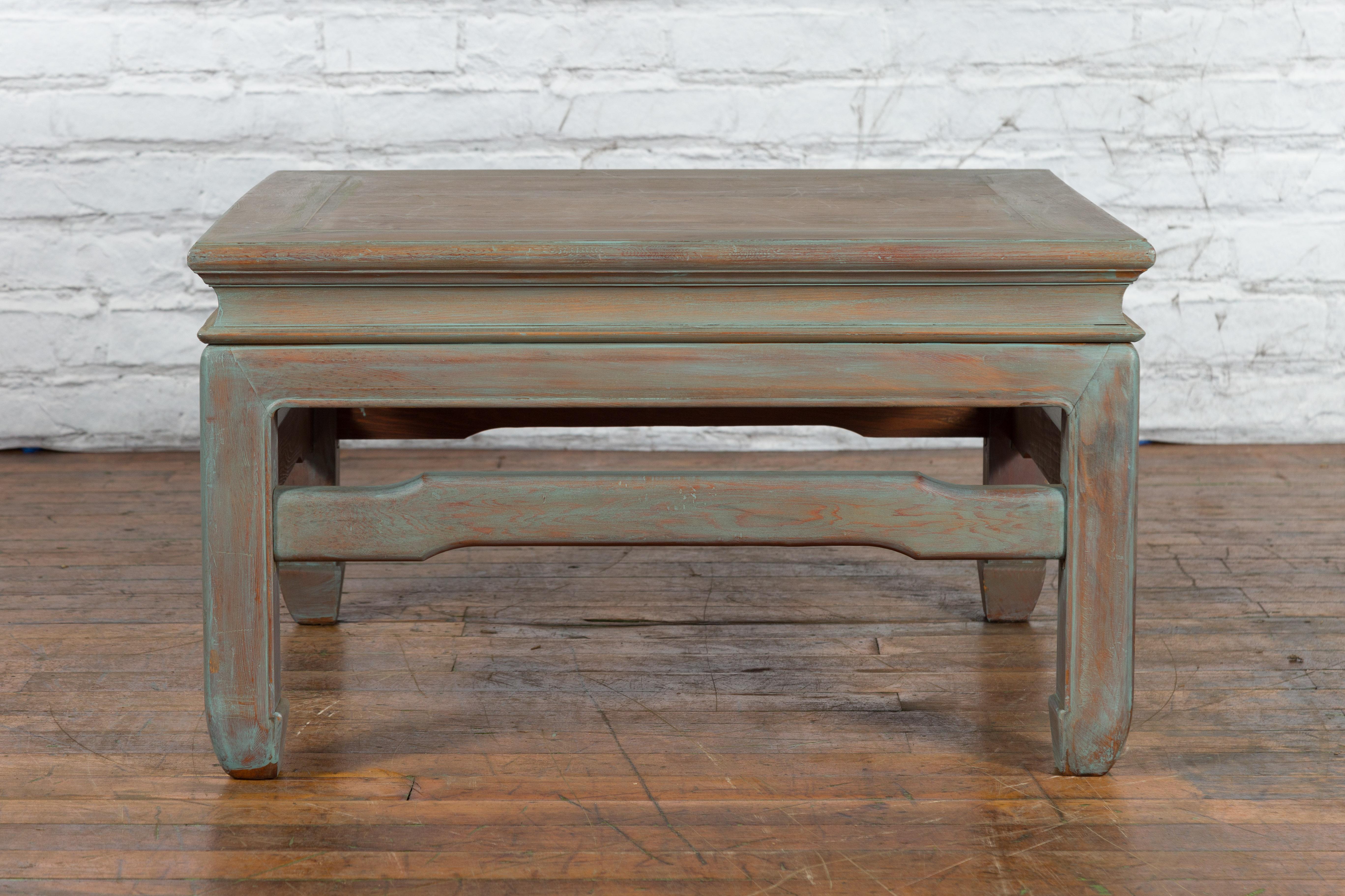 A vintage Thai blue washed teakwood waisted coffee table from the mid 20th century with hump back stretchers and horse hoof legs. Created in Thailand during the Midcentury period, this vintage teakwood coffee table features a blue washed finish
