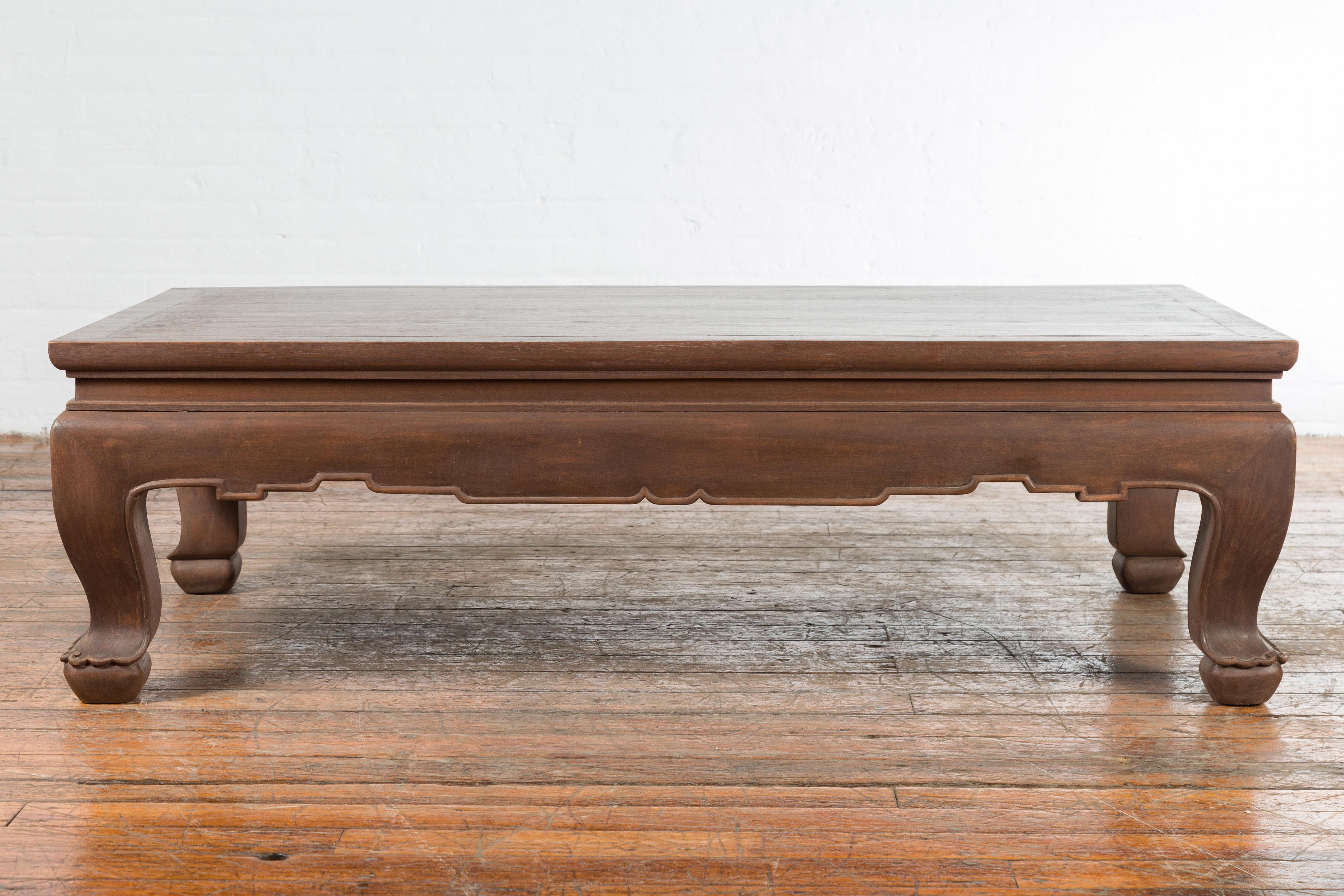 A vintage Thai wooden coffee table from the mid 20th century with waisted carved apron and chow legs. Created in Thailand during the midcentury period, this wooden coffee table features a rectangular top sitting above a waisted carved apron. The