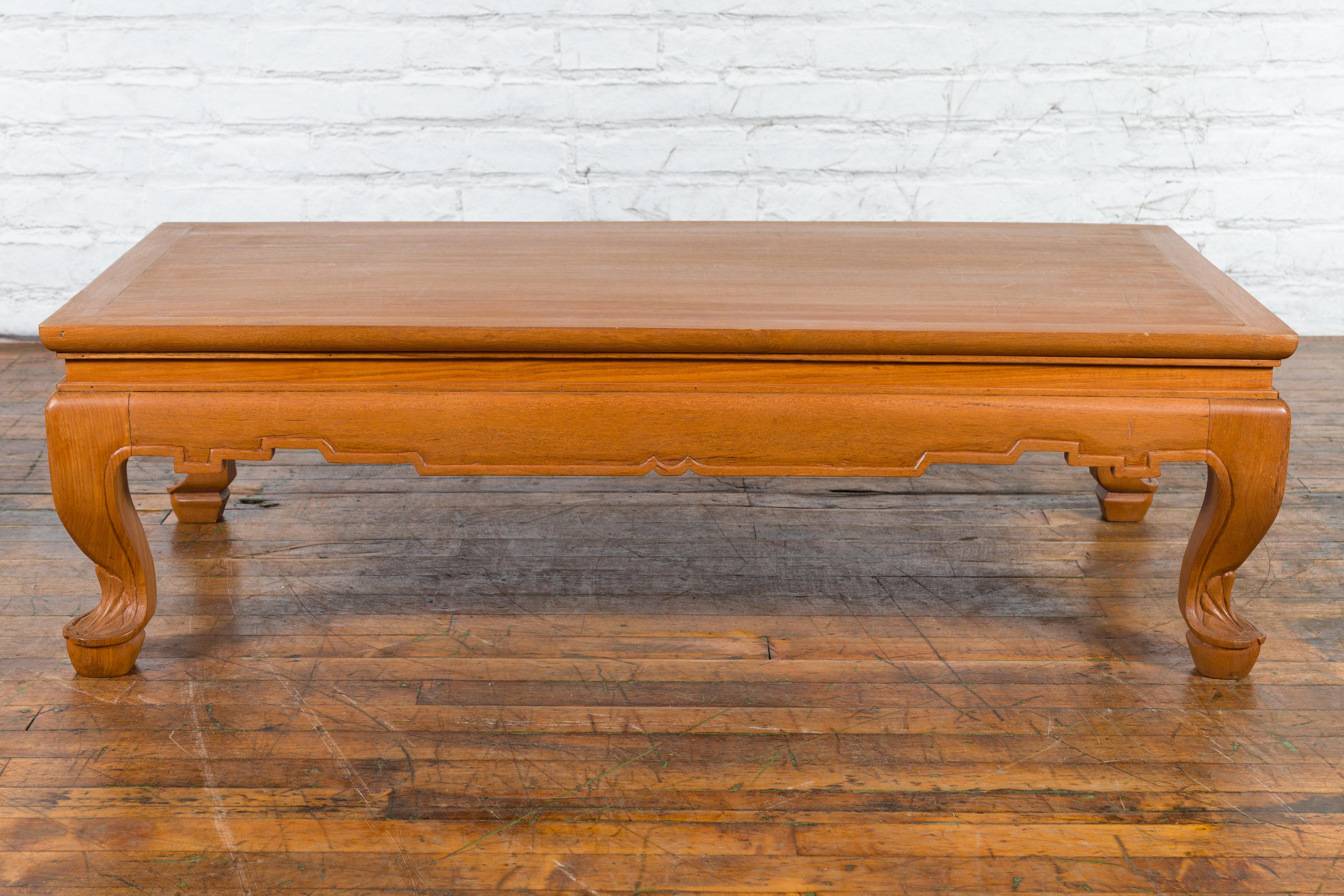 A vintage Thai low wooden coffee table from the mid-20th century, with waisted top, carved apron with linear accents and cabriole legs. Created in Thailand during the mid-century period, this handsome wooden coffee table features a rectangular