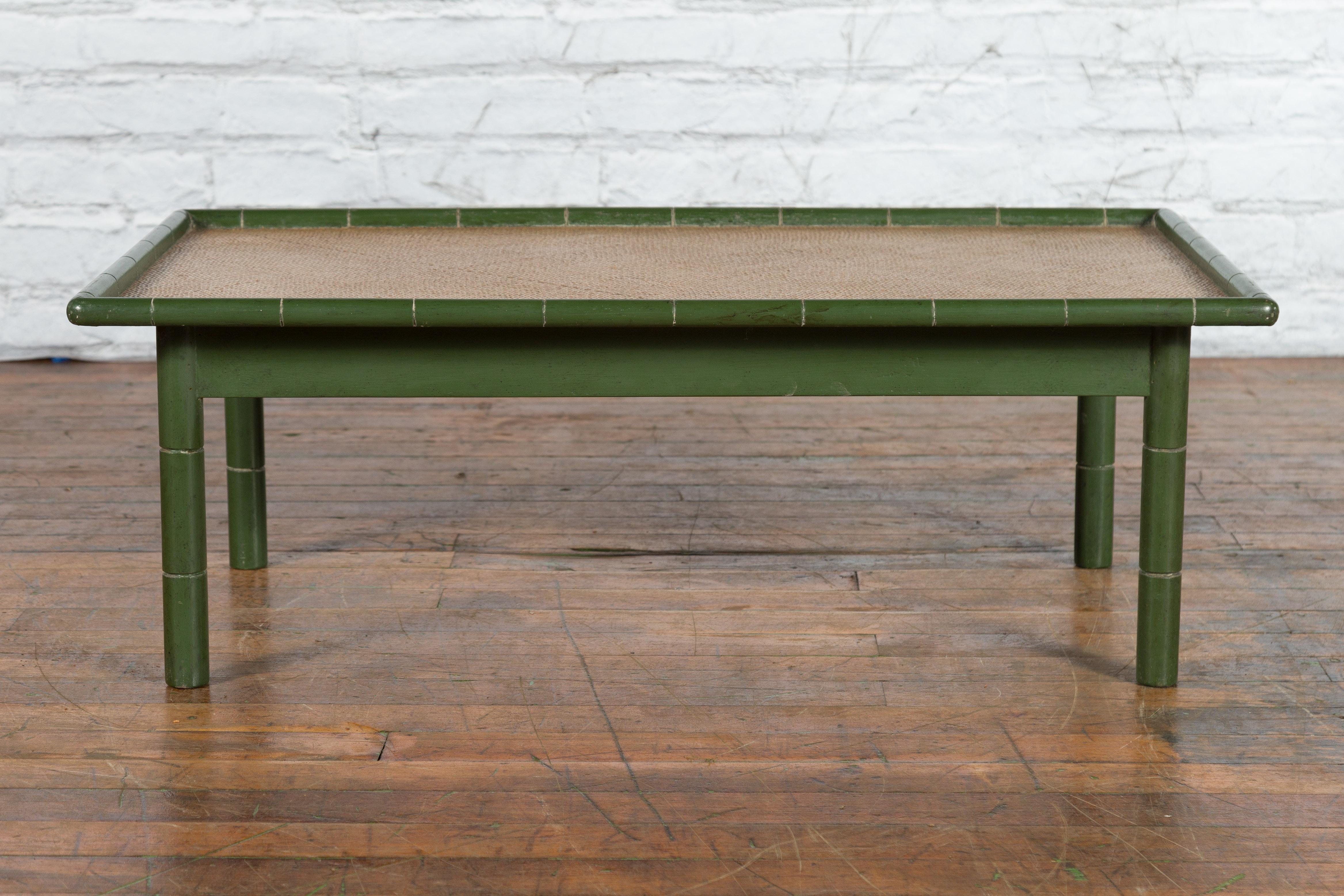 A vintage Country style Thai green painted faux bamboo coffee table from the mid 20th century with woven rattan top and straight legs. Created in Thailand during the Midcentury period, this rustic coffee table features a rectangular woven rattan top