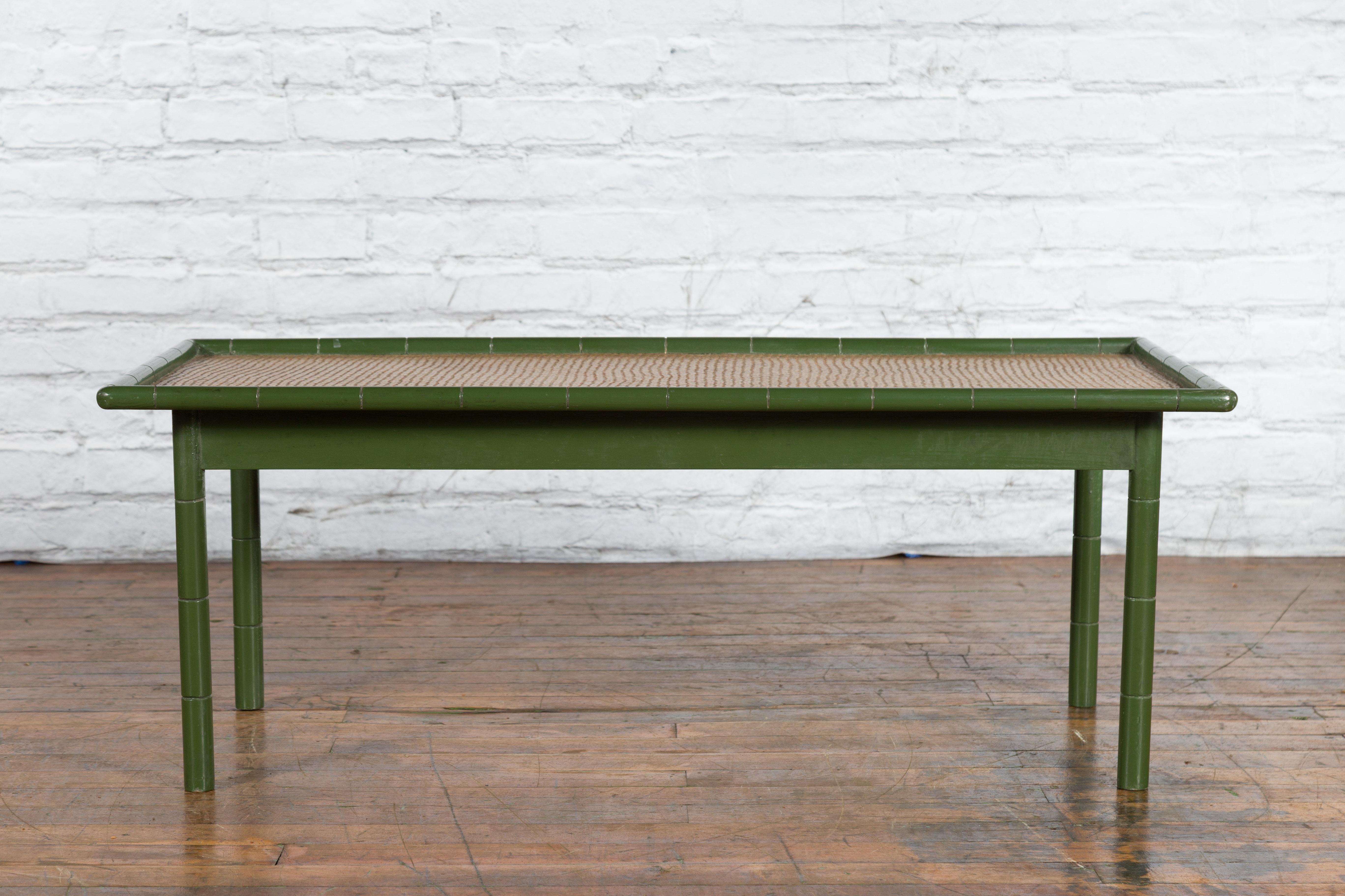 A vintage Country style Thai green painted faux bamboo coffee table from the mid 20th century with woven rattan top and straight legs. Created in Thailand during the Midcentury period, this rustic coffee table features a rectangular woven rattan top