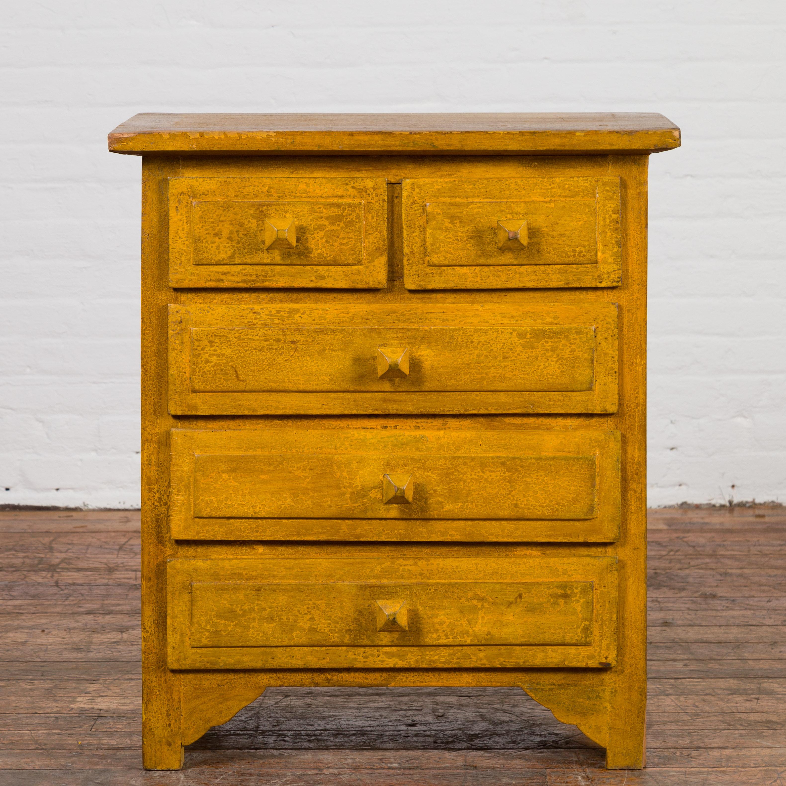 A vintage Thai side chest from the mid 20th century, with mustard glaze, five drawers and distressed patina. Created in Thailand during the midcentury period, this vintage side chest features a rectangular top sitting above five drawers (two small