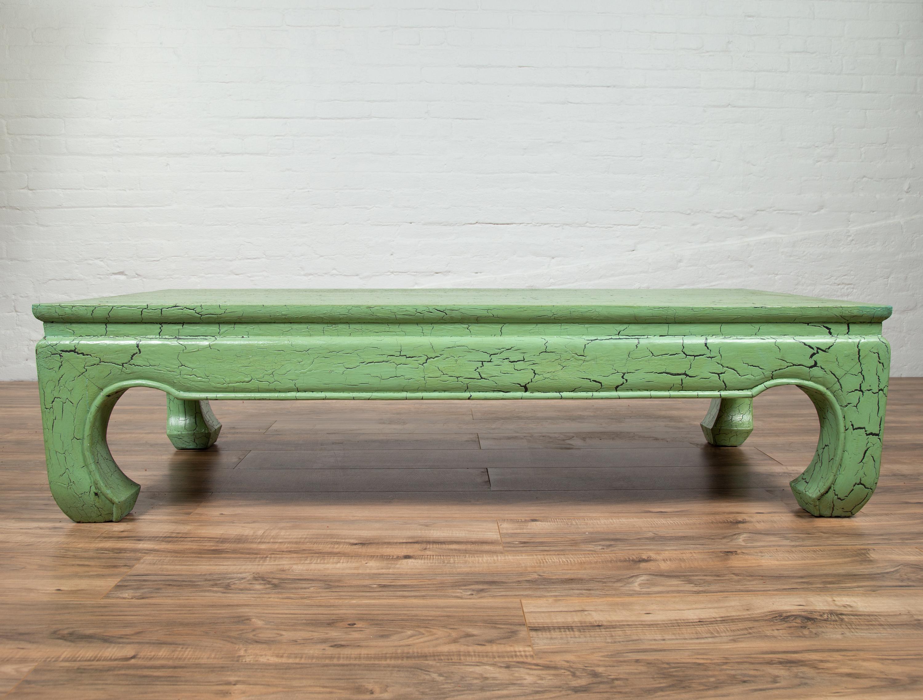 A vintage Thai teak wood long coffee table from the mid-20th century, with distressed green crackled design and chow legs. Born in Thailand during the mid-century period, this stylish teak wood coffee table features an eye-catching green crackled
