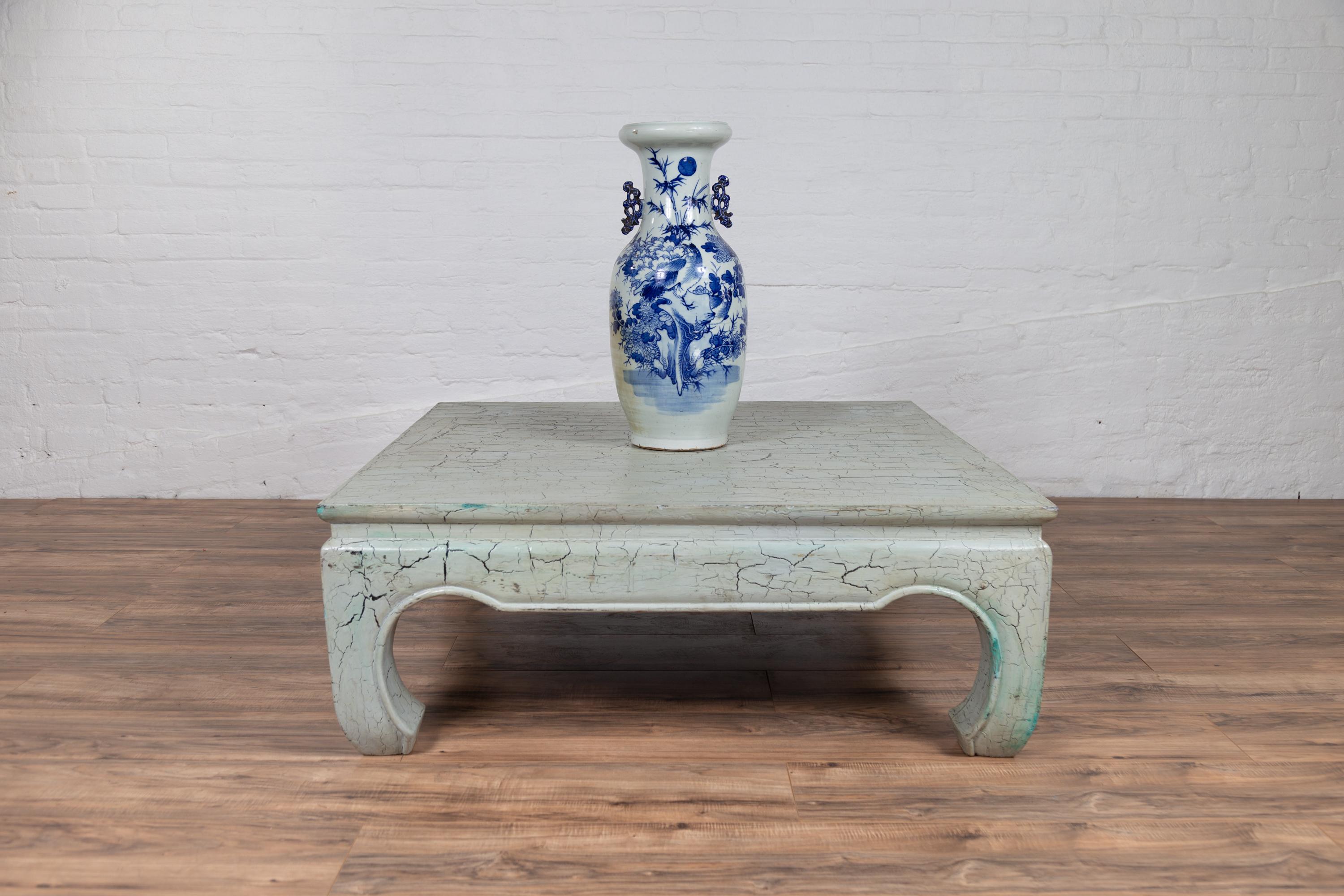 A vintage Ming dynasty style teak wood coffee table from the mid-20th century, with mint green crackled design and chow legs. Born in Thailand during the midcentury period, this vintage Ming dynasty style teak wood coffee table captivates with its