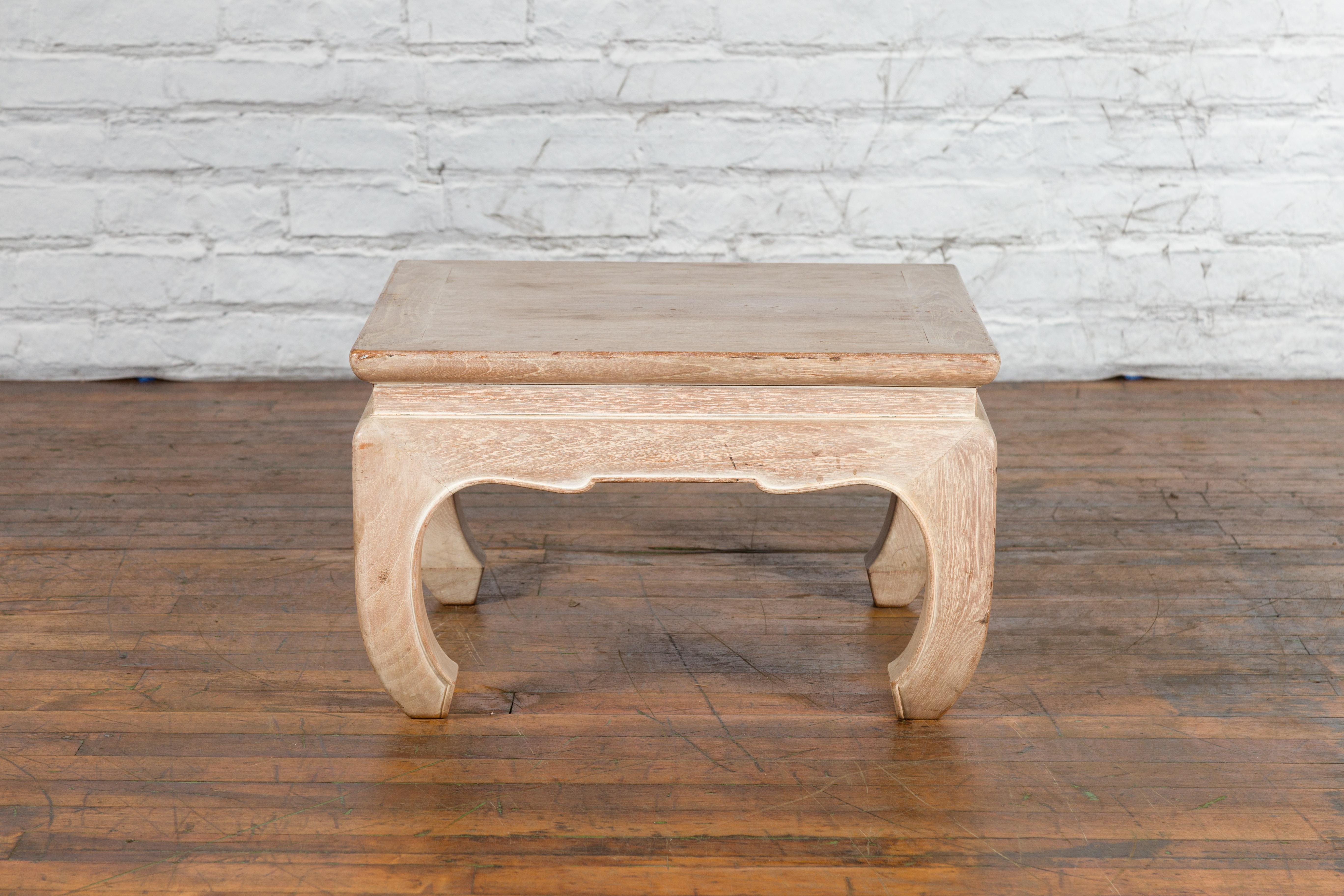 A small vintage Thai whitewashed low drinks table from the mid 20th century, with waisted apron, carved accents and chow legs. Created in Thailand during the Midcentury period, this vintage wooden low drinks table features a square top with central