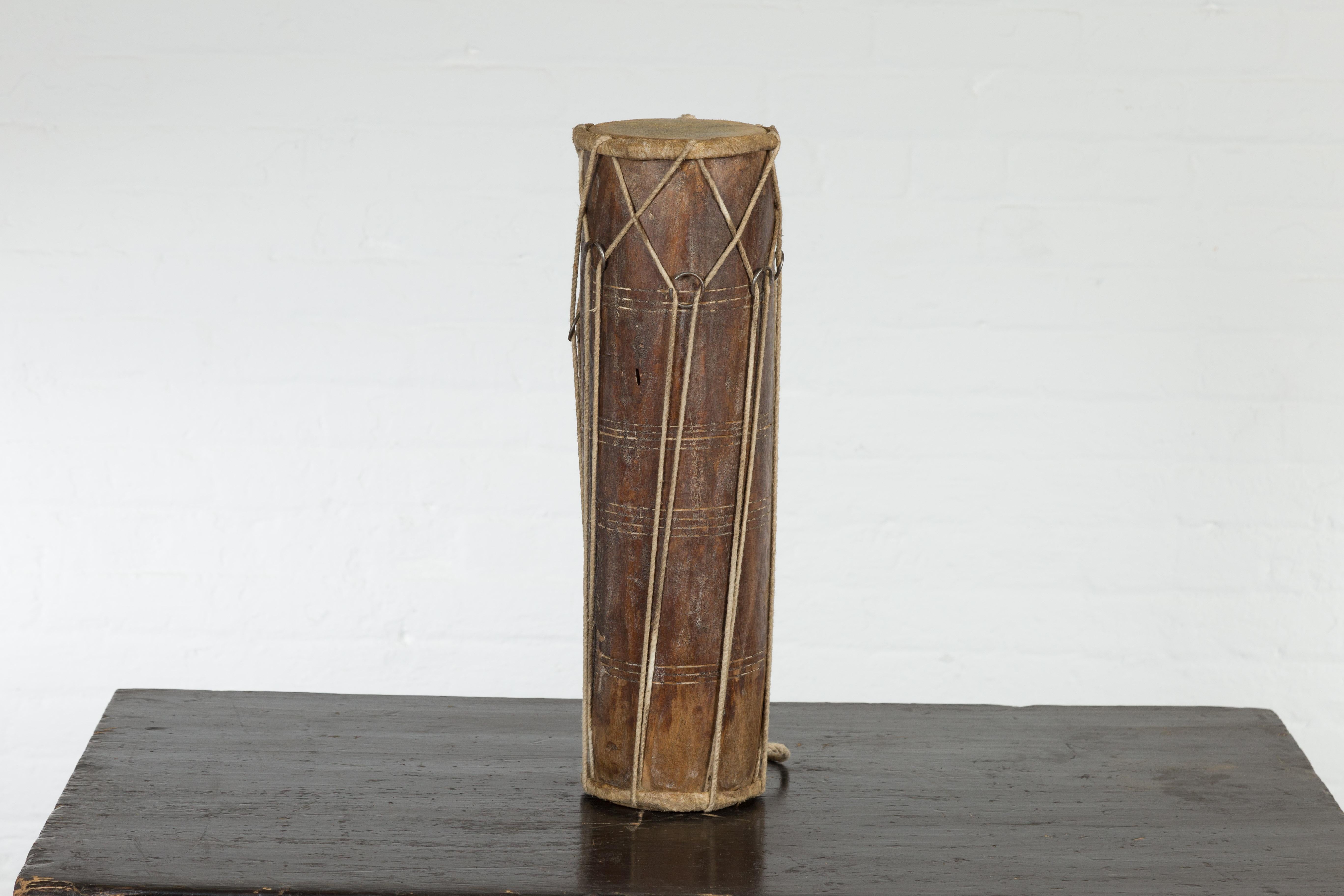 A vintage Thai wood, leather and rope Klong Khaek processional drum from the mid 20th century, with ties and weathered patina. Created in Thailand during the midcentury period, this Klong Khaek drum was likely used in Thai ensembles for processions.