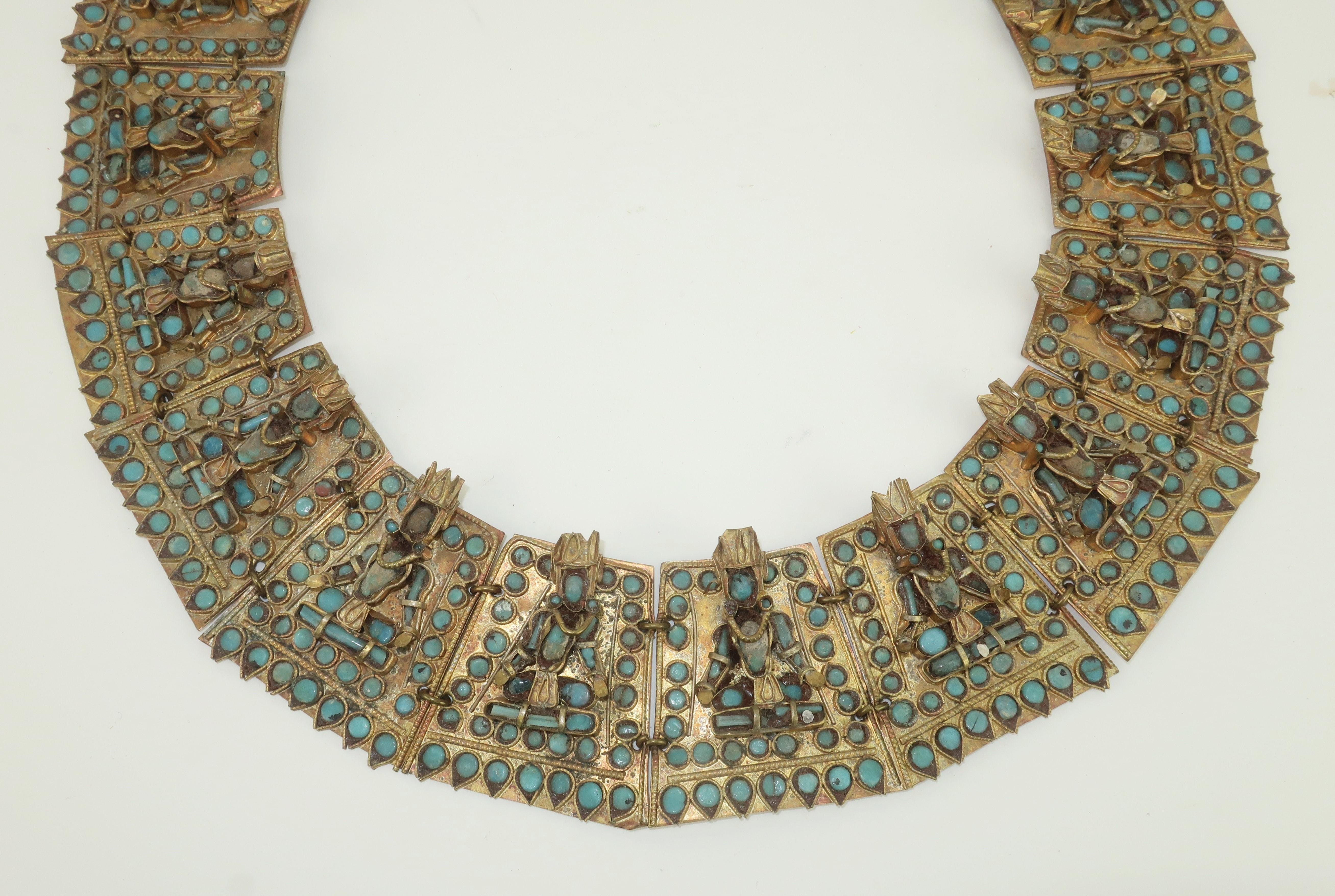 Vintage collar necklace in a brass metal with intricate filigree and costumed figures embellished with turquoise glass beads.  The figures are dancing and in prayerful positions with traditional head wear and necklaces.  There are two hook closures