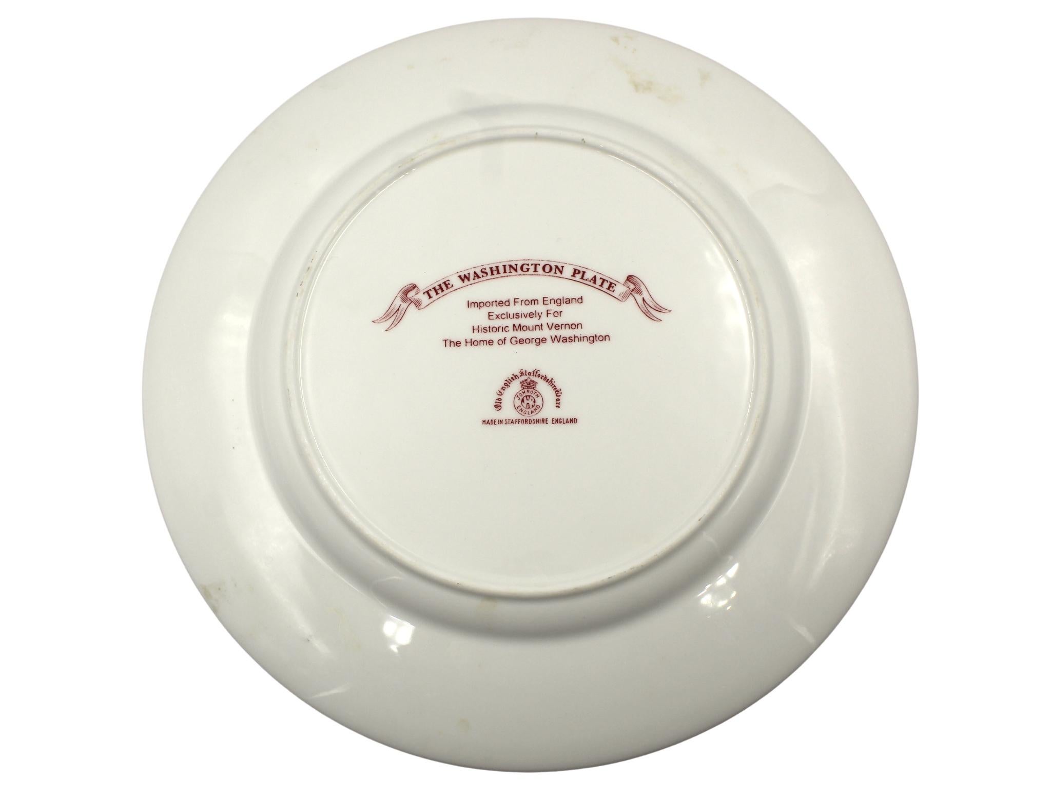 Presented is a red-glazed transferware plate, originally imported by Jon Roth for sale at the Historic Mount Vernon estate. Made in Staffordshire, England, this specific pattern celebrates our first President and First Lady, George and Martha