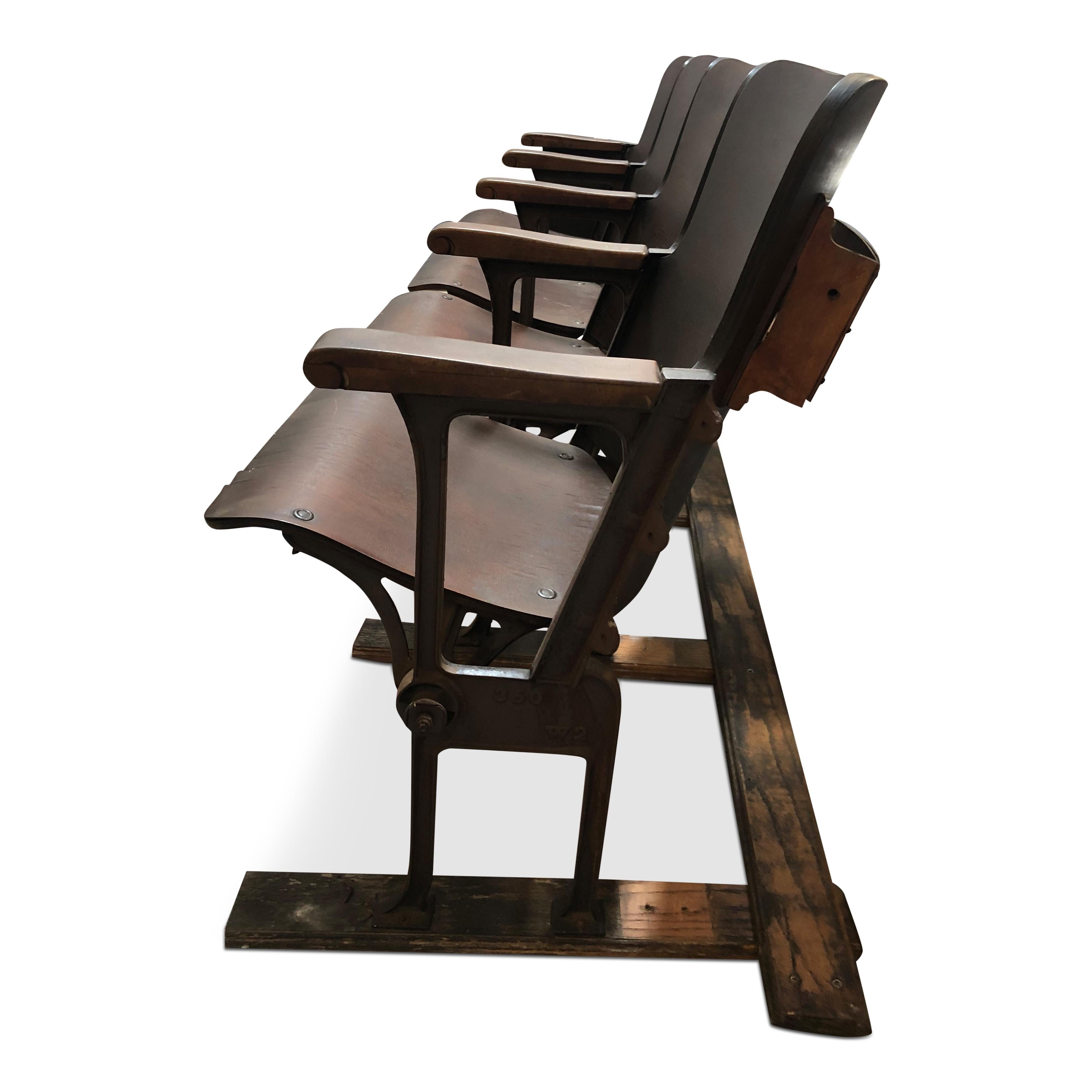 Diese Theatersitze im Industriestil sind aus gebogenem Sperrholz gefertigt und die Armlehnen sind aus Massivholz. Die Struktur und die Sitzmechanik sind aus Stahl gefertigt. Die Sitze können hochgeklappt werden, und der Sockel kann entweder