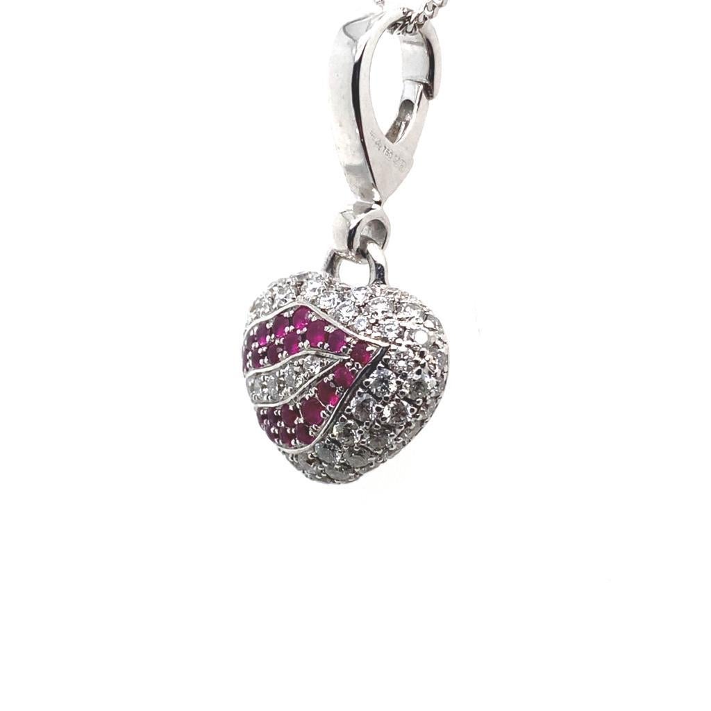 A vintage Theo Fennell diamond and ruby heart lips charm pendant in 18 karat white gold.

Created as a miniature heart, featuring pavé set ruby lips set within a round brilliant cut diamond surround, the red of the ruby contrasting beautifully