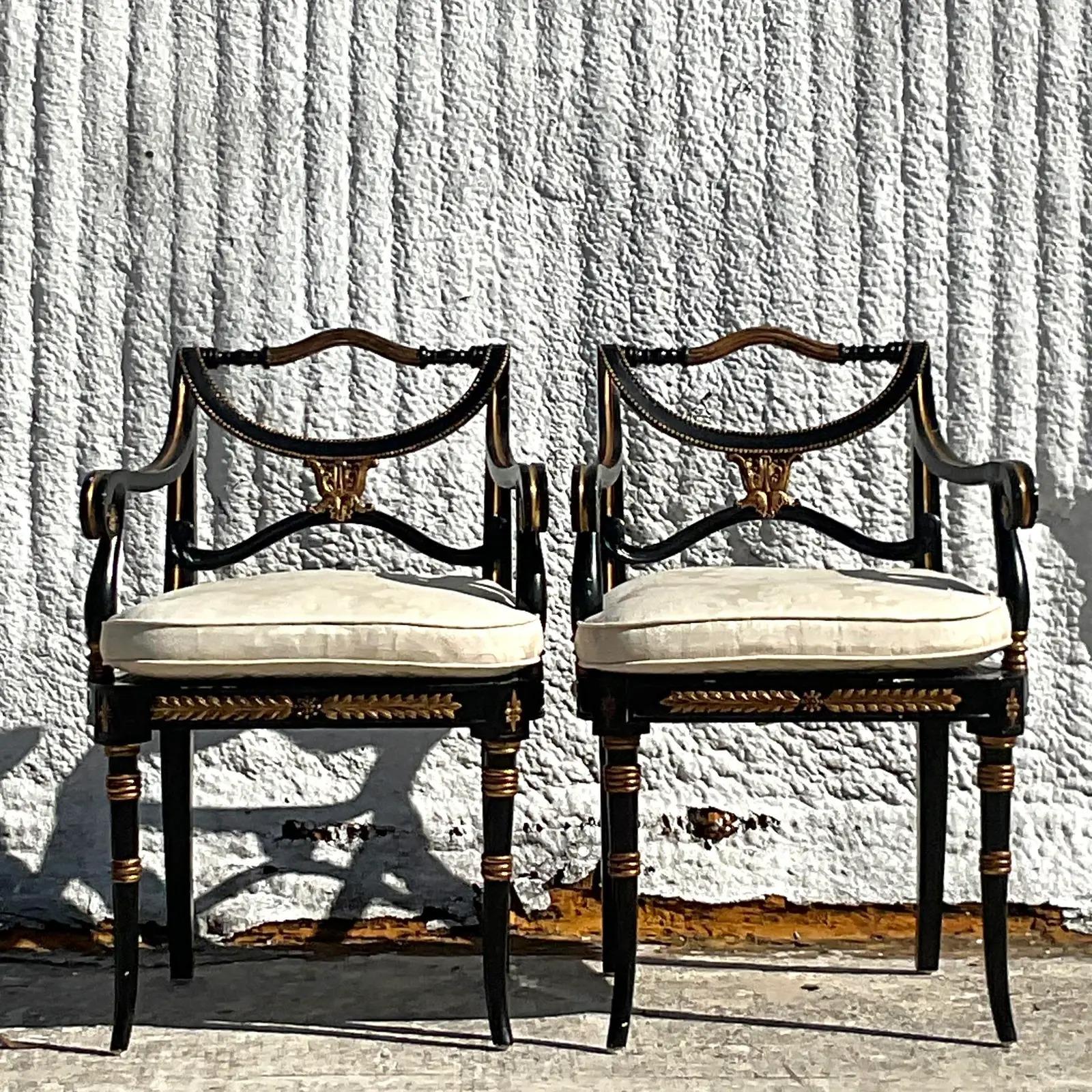 A fabulous pair of vintage Regency arm chairs. Made by the iconic Theodore Alexander group. Beautiful hand carved detail with inset cane panels. Gorgeous gilt touches on a gloss black frame. Acquired from a Palm Beach estate.