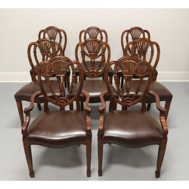 A set of eight dining chairs in the Hepplewhite style by Theodore Alexander of Hickory, North Carolina, USA. Mahogany with carved seatbacks, brown leather upholstered seats with nailhead trim, and tapered legs with spade front feet. Six side chairs