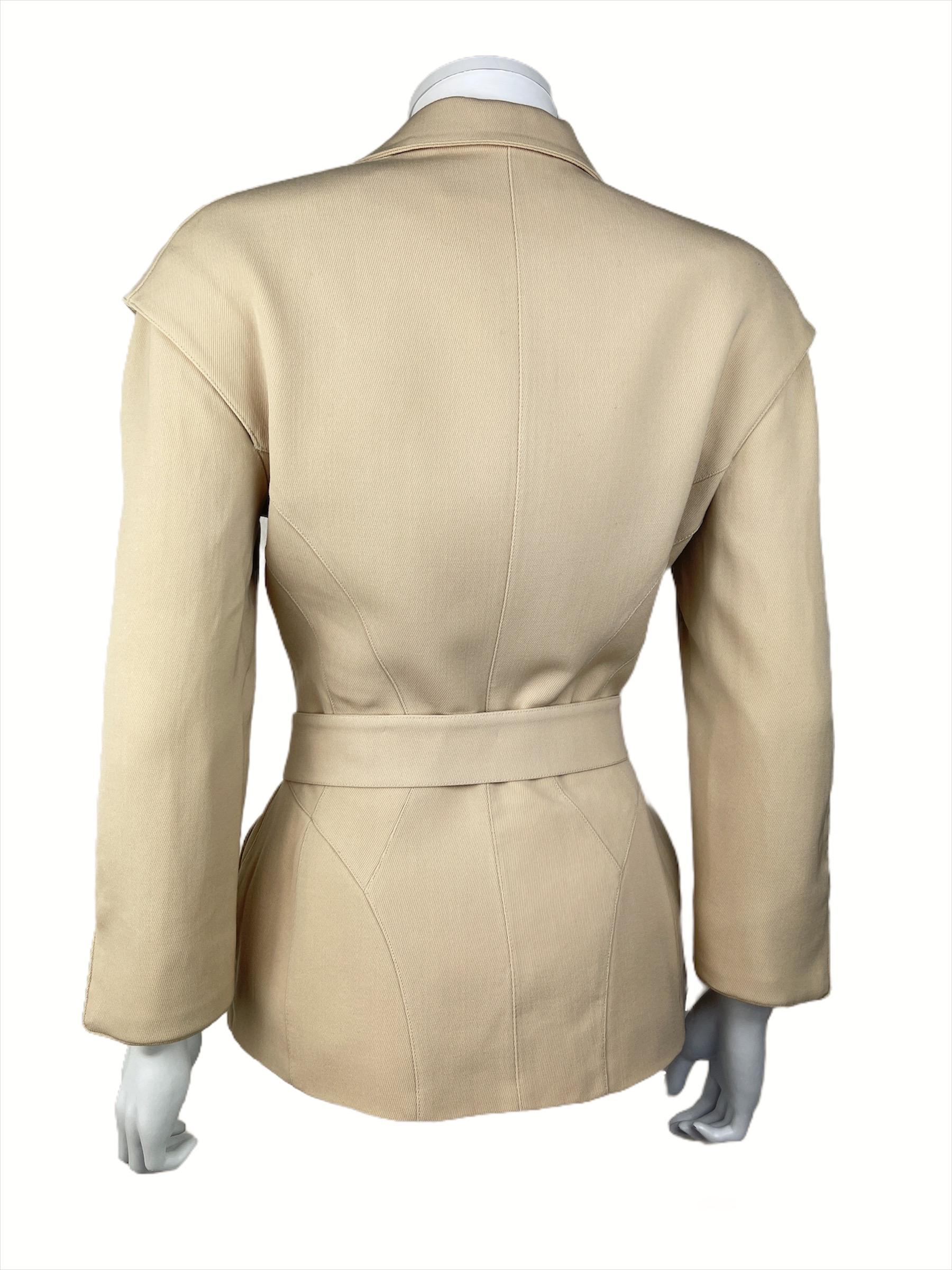 THIERRY MUGLER, Made in France circa 90’s.
Beautiful lined futuristic jacket made in a beige worsted wool. It has two pockets, a belt and a transversal zipper. It also has removable shoulder pads.
The belt has a graphic metallic signed hardware.
