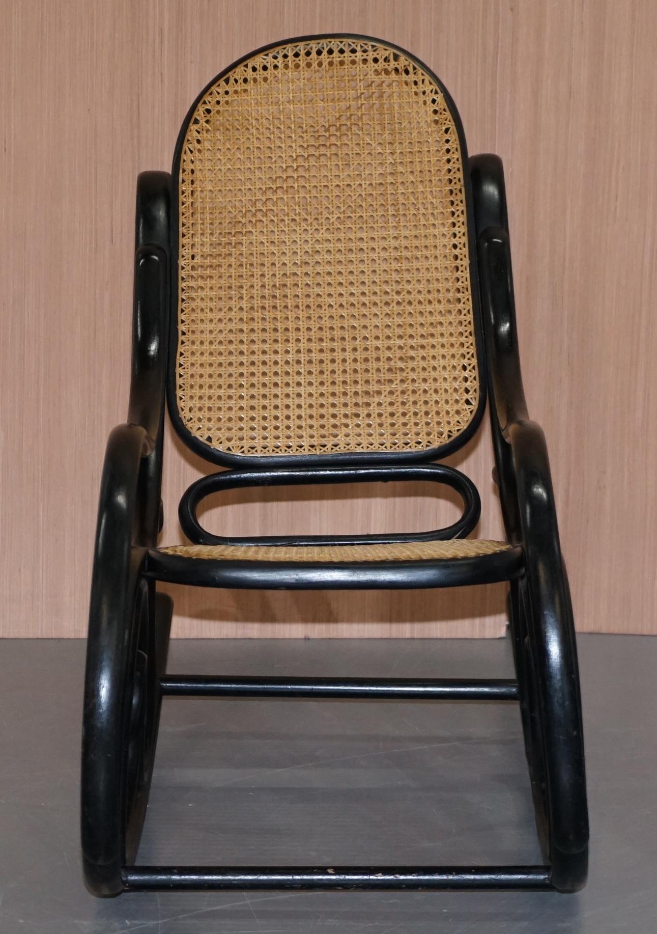Nous sommes ravis de proposer à la vente ce joli petit fauteuil à bascule vintage Thonet avec un cadre noir ébonisé et un siège en rotin.

Conçue à l'origine dans les années 1800 avec des courbes élaborées et un siège et un dossier en canne