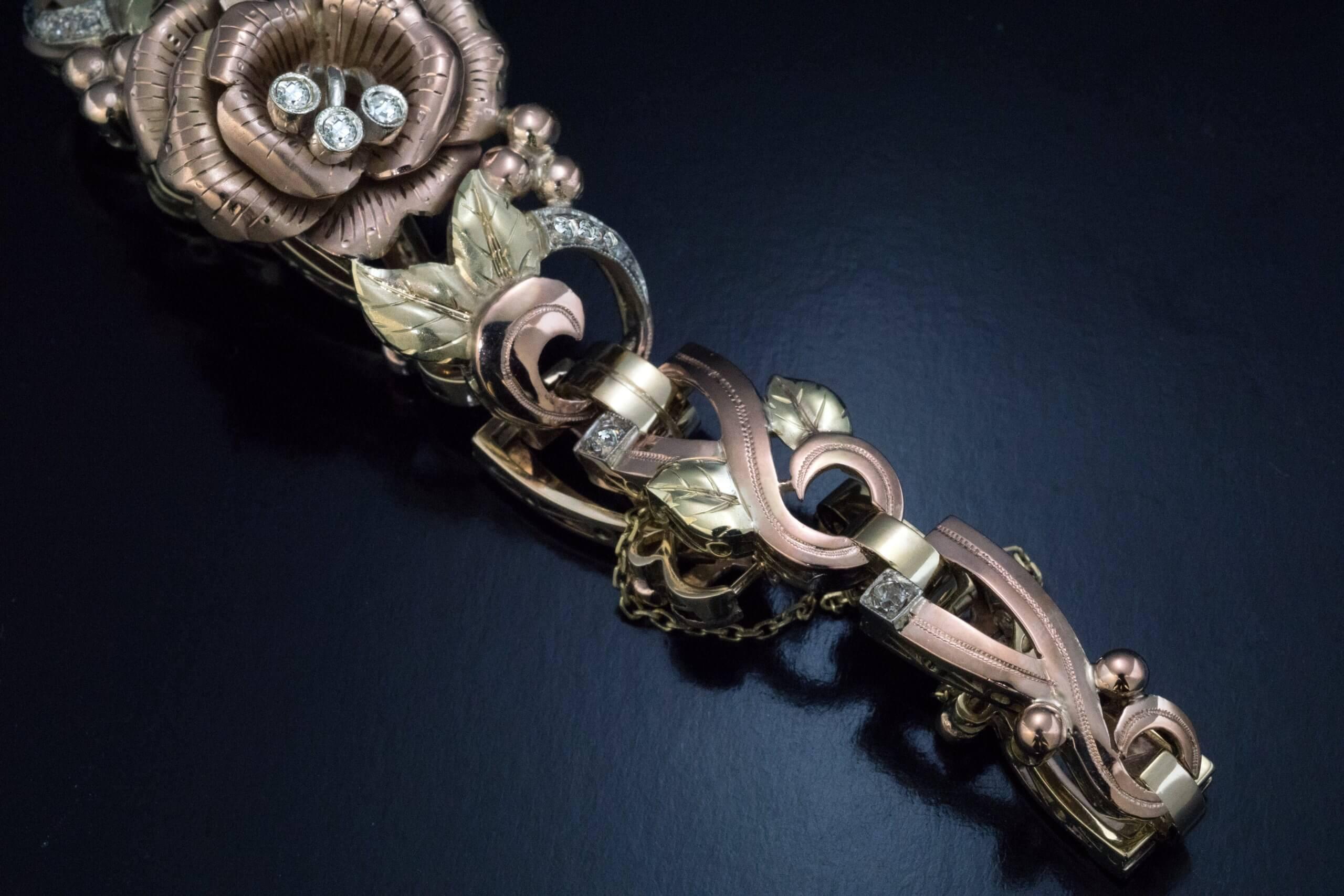 This ornate Art Deco era floral motif bracelet was made in Romania in the late 1920s – early 1930s.  The bracelet is finely crafted in rose, green, and white 14K gold and accented with small old cut diamonds.  Marked on clasp with wolf’s head