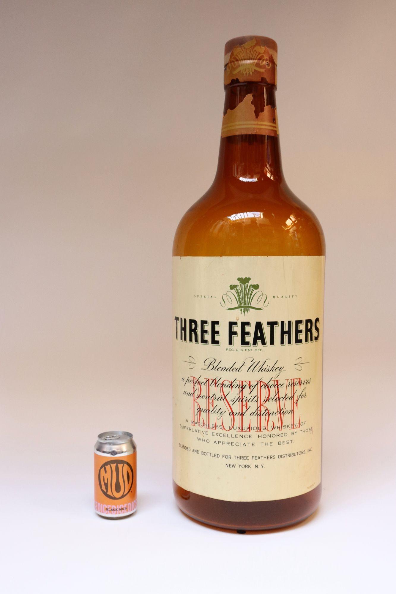 Bouteille publicitaire/présentoir de magasin surdimensionné pour Three Feathers Whiskey (vers les années 1940, États-Unis).
Composé d'un verre ambré avec deux étiquettes et un bouchon en bois d'origine.
Présence de taches à l'intérieur du verre