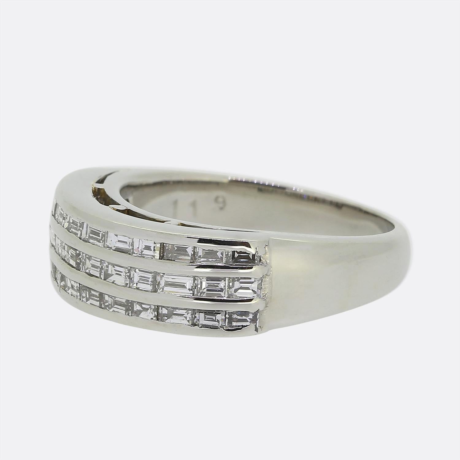 Ecco un anello di diamanti in platino elegante e raffinato. Questo pezzo vintage presenta tre file di diamanti bianchi dritti con taglio a baguette, creando un look audace ed elegante. I diamanti sono incastonati in un'ampia fascia lucida che esalta