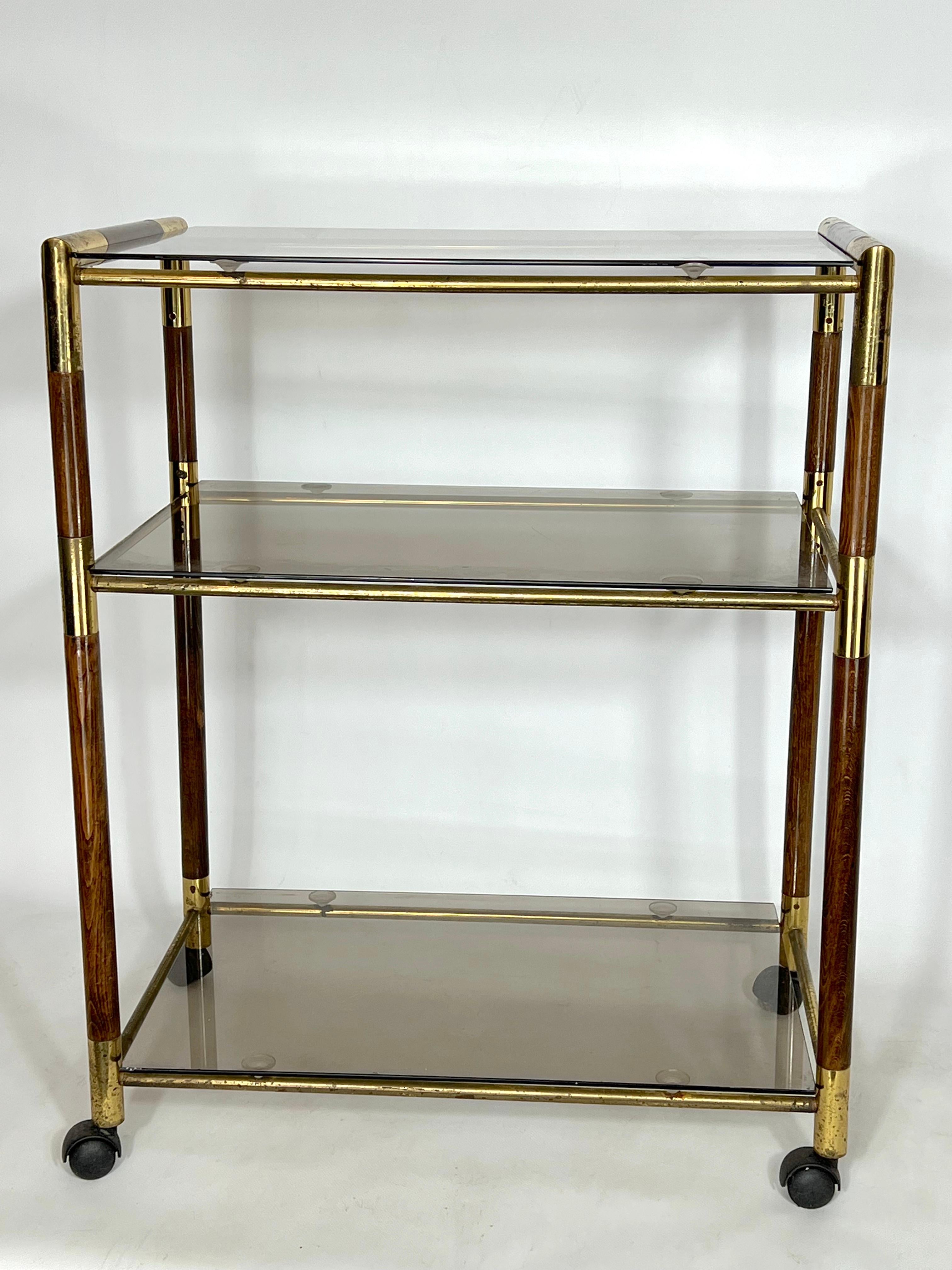 Elegant Vintage three shelves trolley or bar cart designed by the Italian Tommaso Barbi during 1970s. It is made from brass and wood. Brass with some patina and spots.