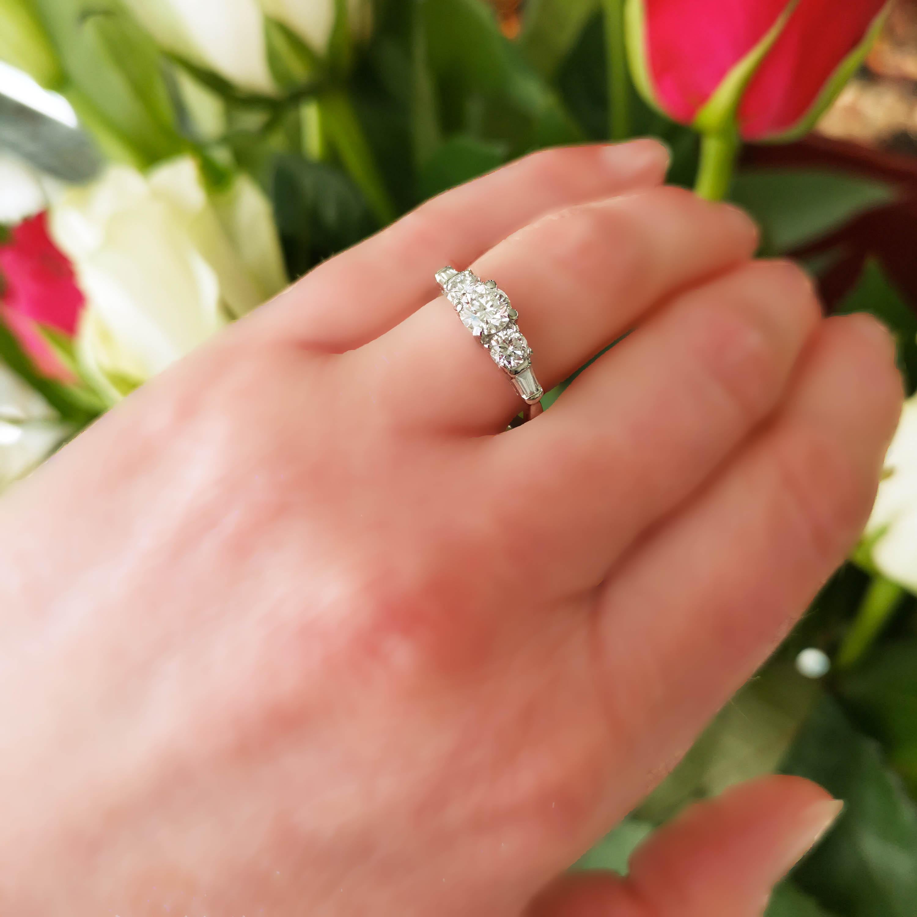 A vintage three stone diamond ring, set with a 0.59 carat, F colour, I1 clarity, round brilliant-cut diamond, with a round brilliant-cut diamond set either side, each weighing 0.28 carat, F colour, one is I1 clarity, the other is I2, in four claw