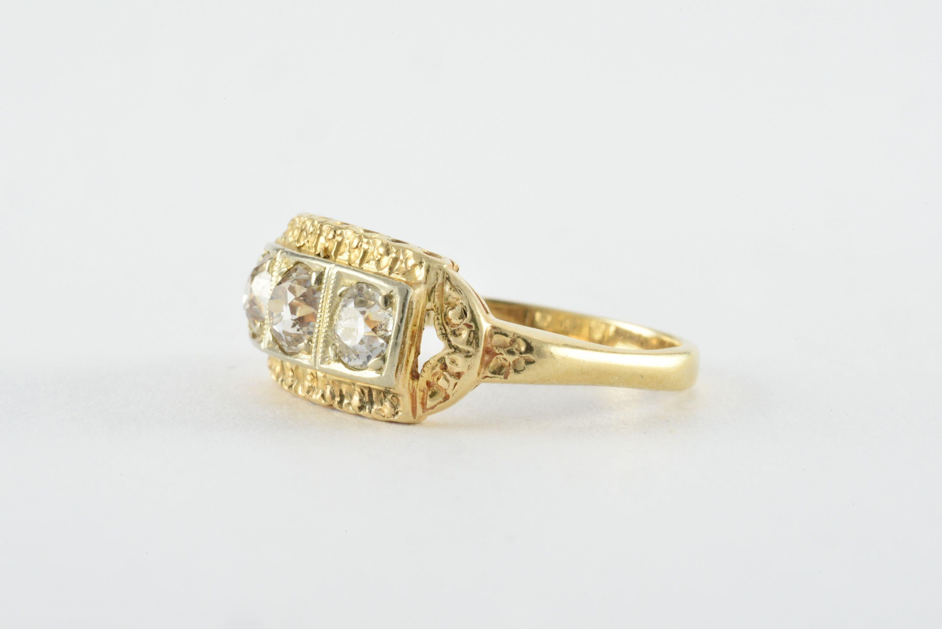 A trio of Old European cut diamonds set in 14kt white gold totaling approximately 0.75 carats, J-K color, SI2 clarity, elegantly line this vintage band crafted from 14kt yellow gold and elaborate etching. 
