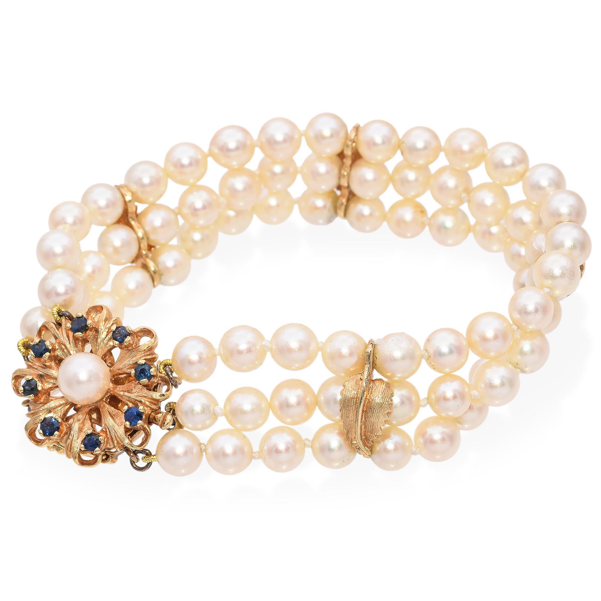 Elegantes Vintage Perlenarmband. Dieses exquisite Armband besteht aus drei Strängen mit schimmernden Perlen, die sorgfältig zu einem zeitlosen Schmuckstück arrangiert wurden. Das Herzstück ist ein atemberaubendes, in Gold gefertigtes Blumenmotiv mit