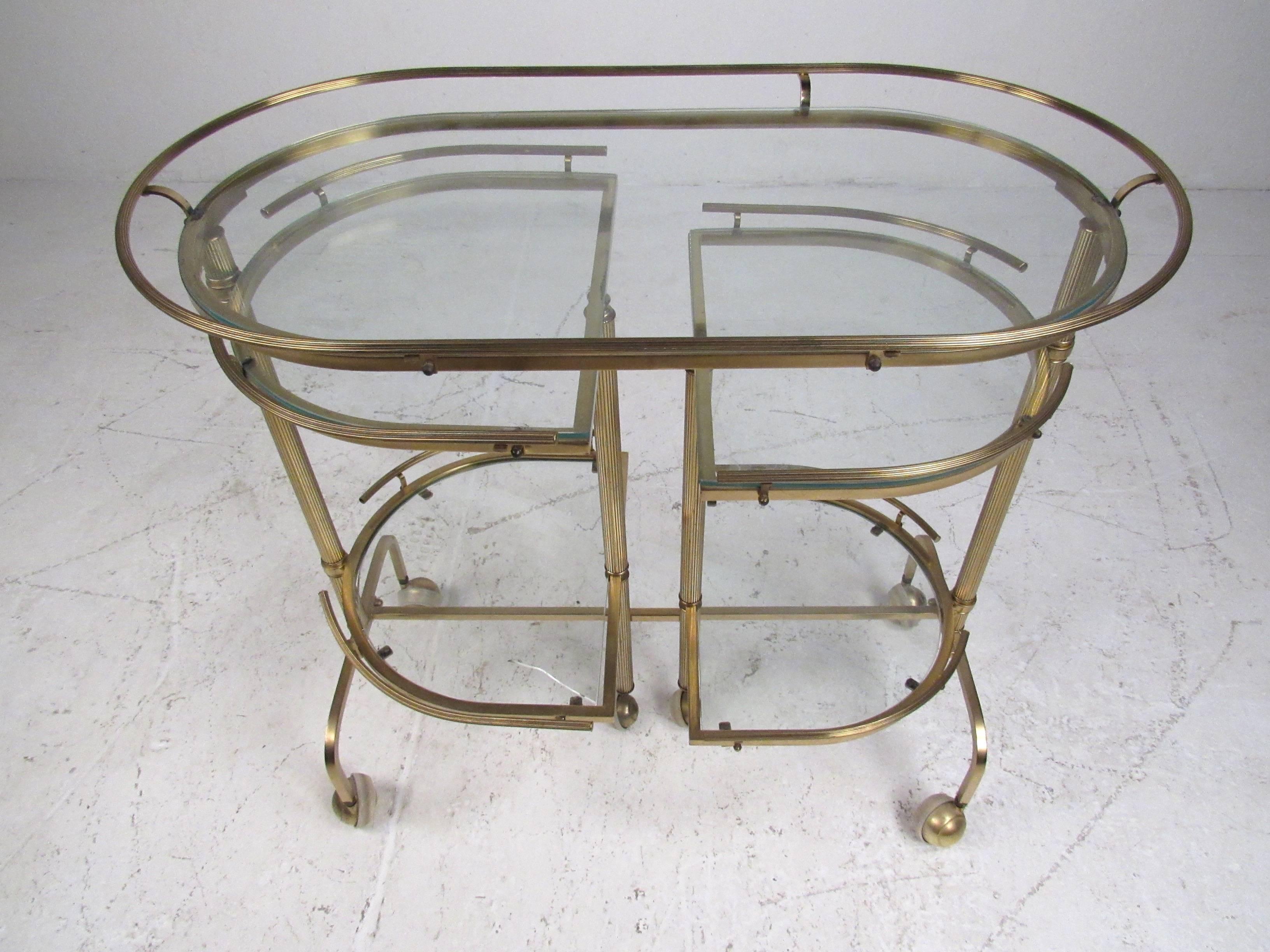 Unusual three-tier service/bar cart with fluted rails and glass shelves that swivel to open at various positions revealing five surfaces for optimum usage. Fully extended the cart measures 56