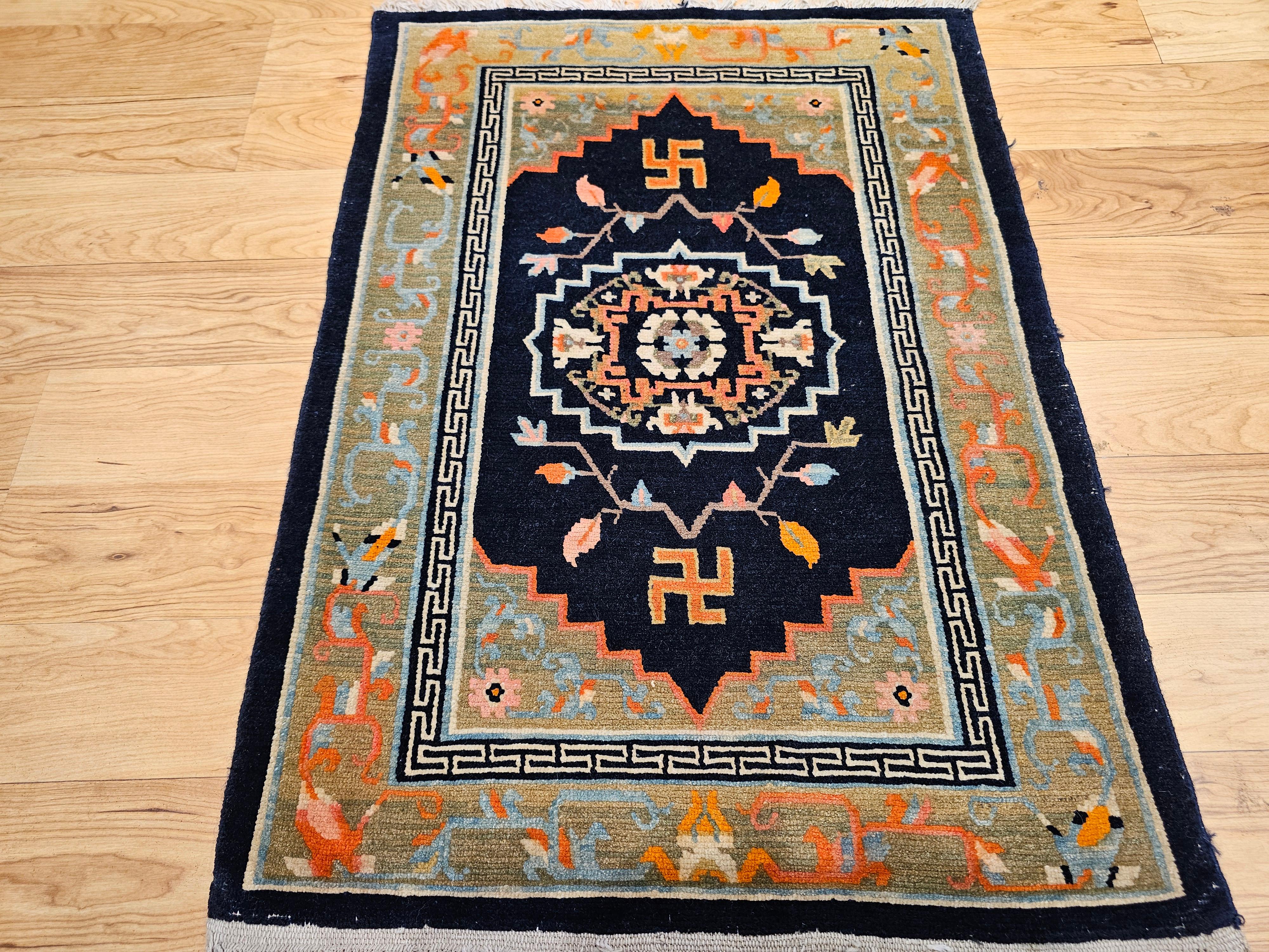 This vintage Tibetan rug is a striking and meaningful piece, featuring a bold medallion design set against a deep black field, beautifully framed by a pale green border and a delicate narrow lattice band. The rug is richly detailed with accents in