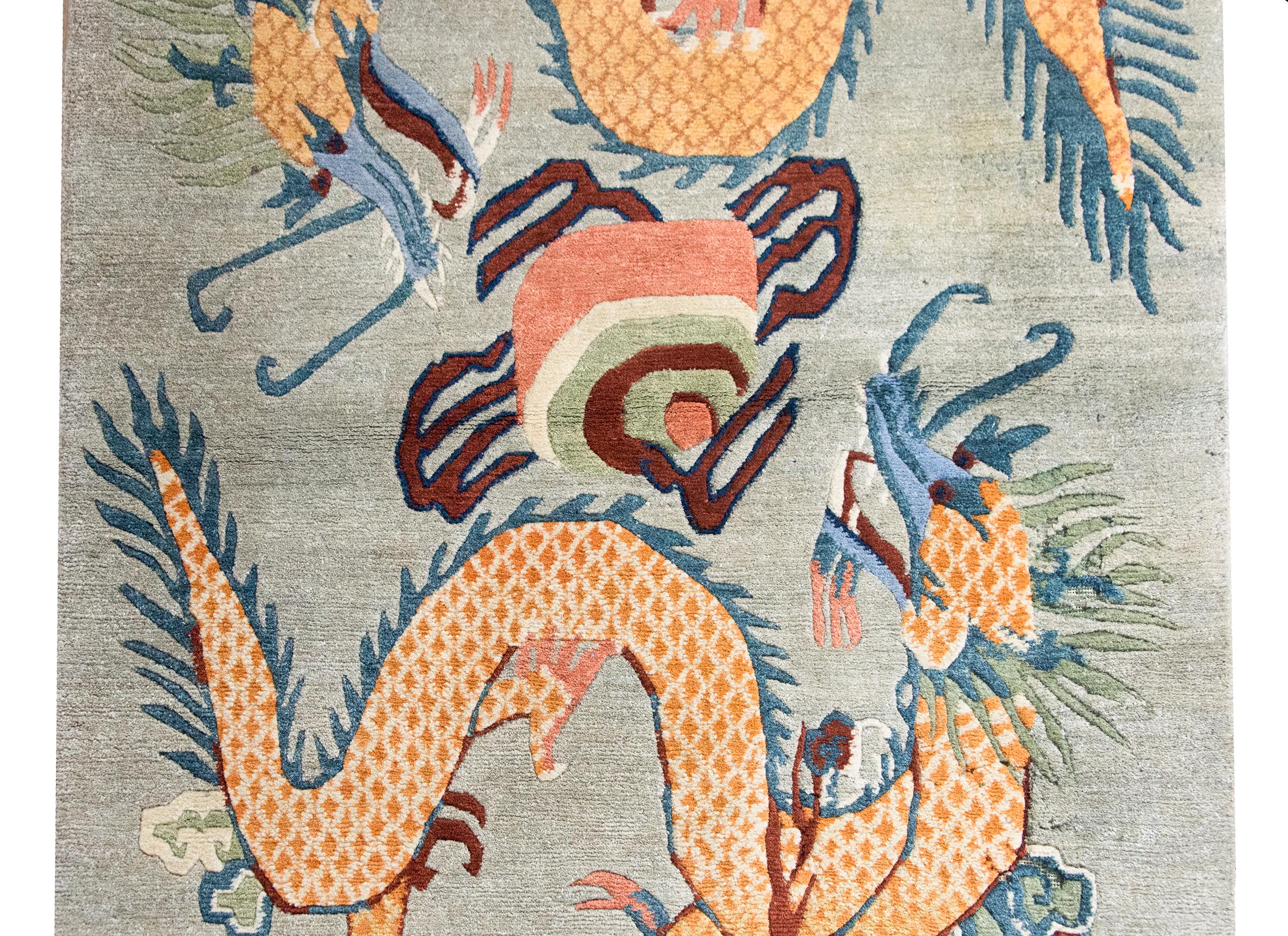 A striking late 20th century Tibetan hand-knotted wool rug with double dragons swirling around a pearl of truth, and with turbulent storm clouds at each end, and all woven in indigos, oranges, reds, and greens.  