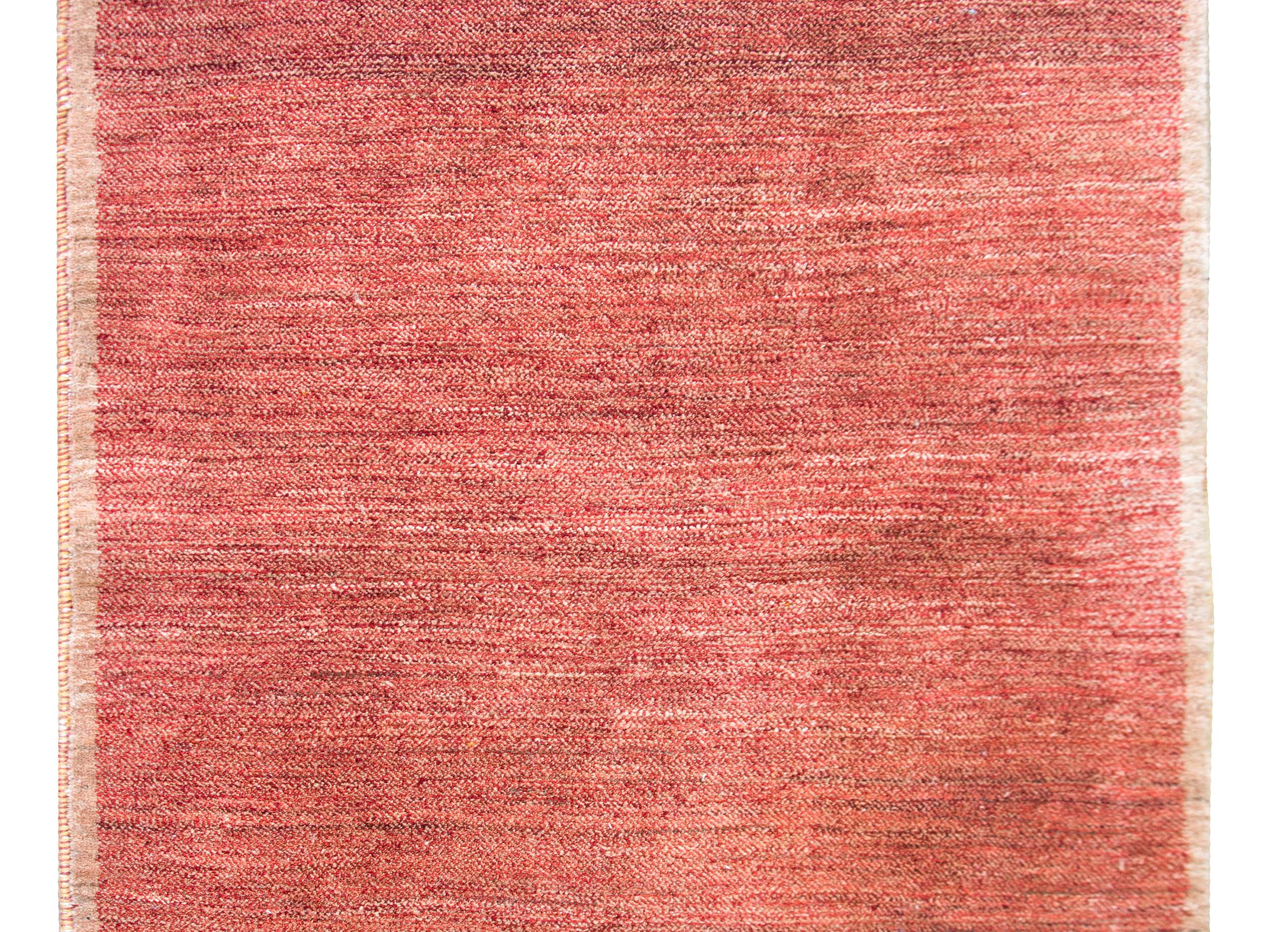 A serene late 20th century Tibetan hand-knotted rug with a weathered cranberry and brown field surrounded by a thin brown border.