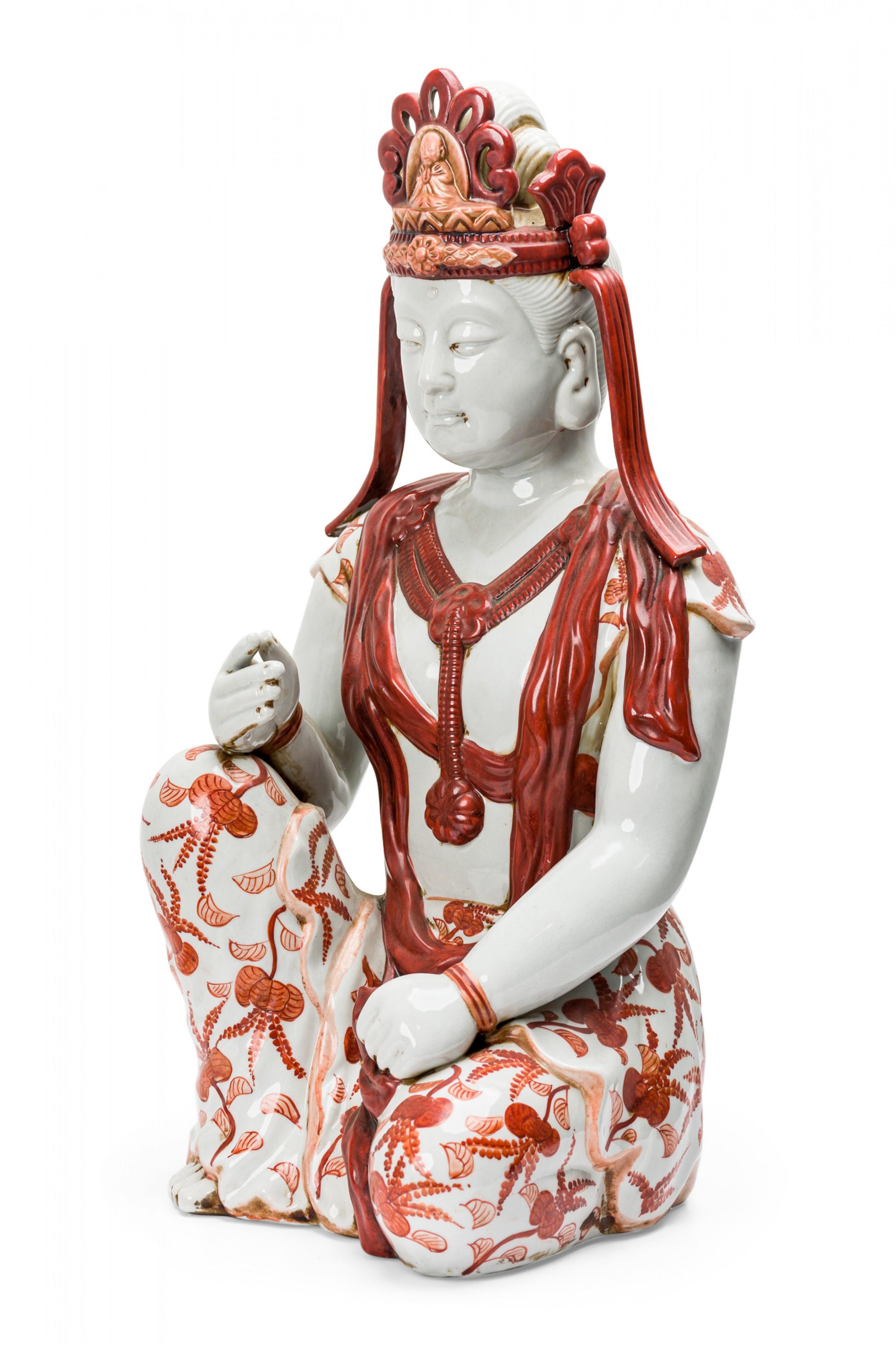 Vintage tibetische Porzellanstatue, die einen sitzenden Buddha darstellt, mit handgemalten orangefarbenen Details.