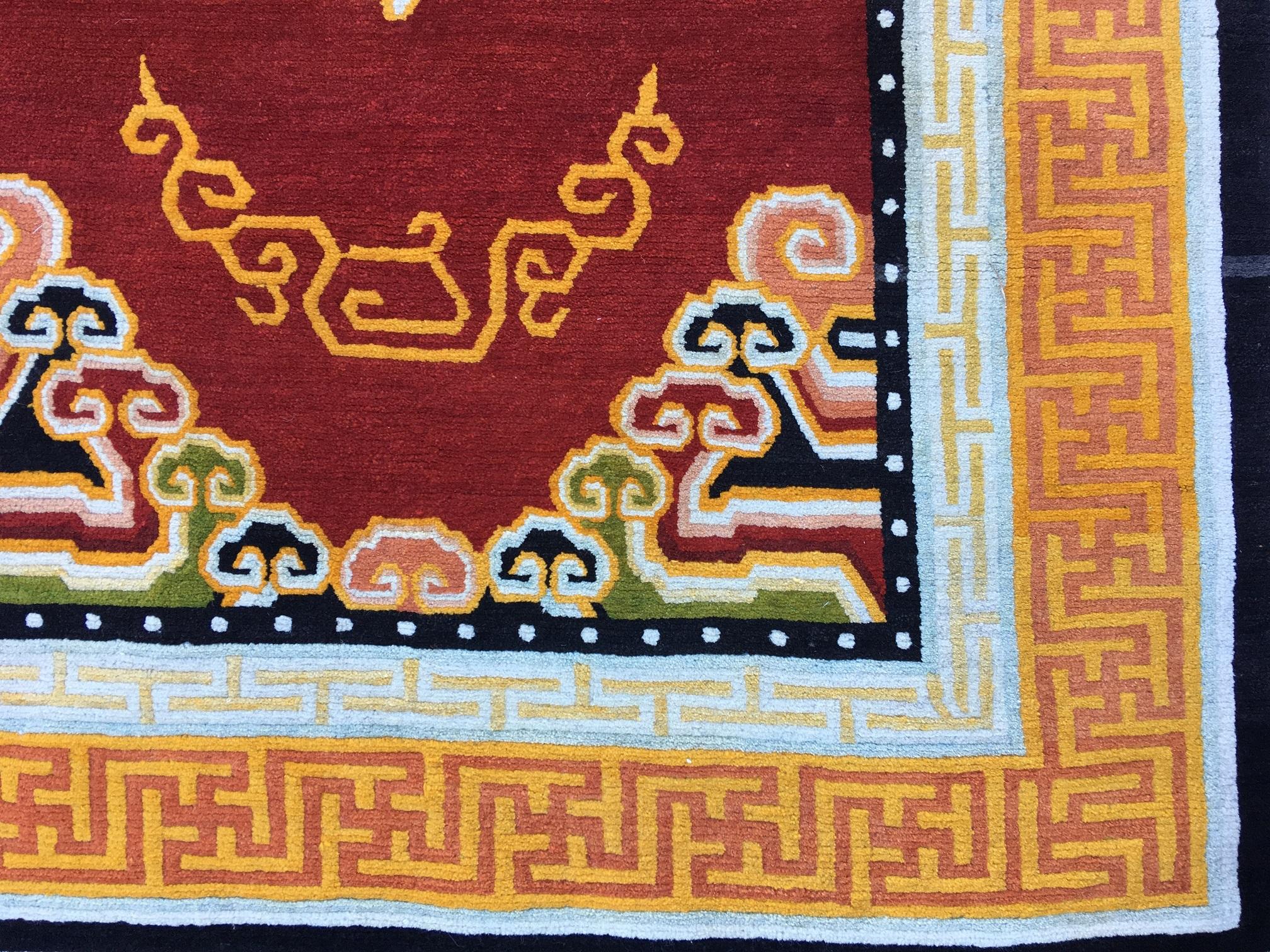 A fabulous 1930s Tibetan rug with a simple cloudband design on an open red field surrounded by a red and gold key border. One of a pair! Measures: 2.12m x 1.24m.