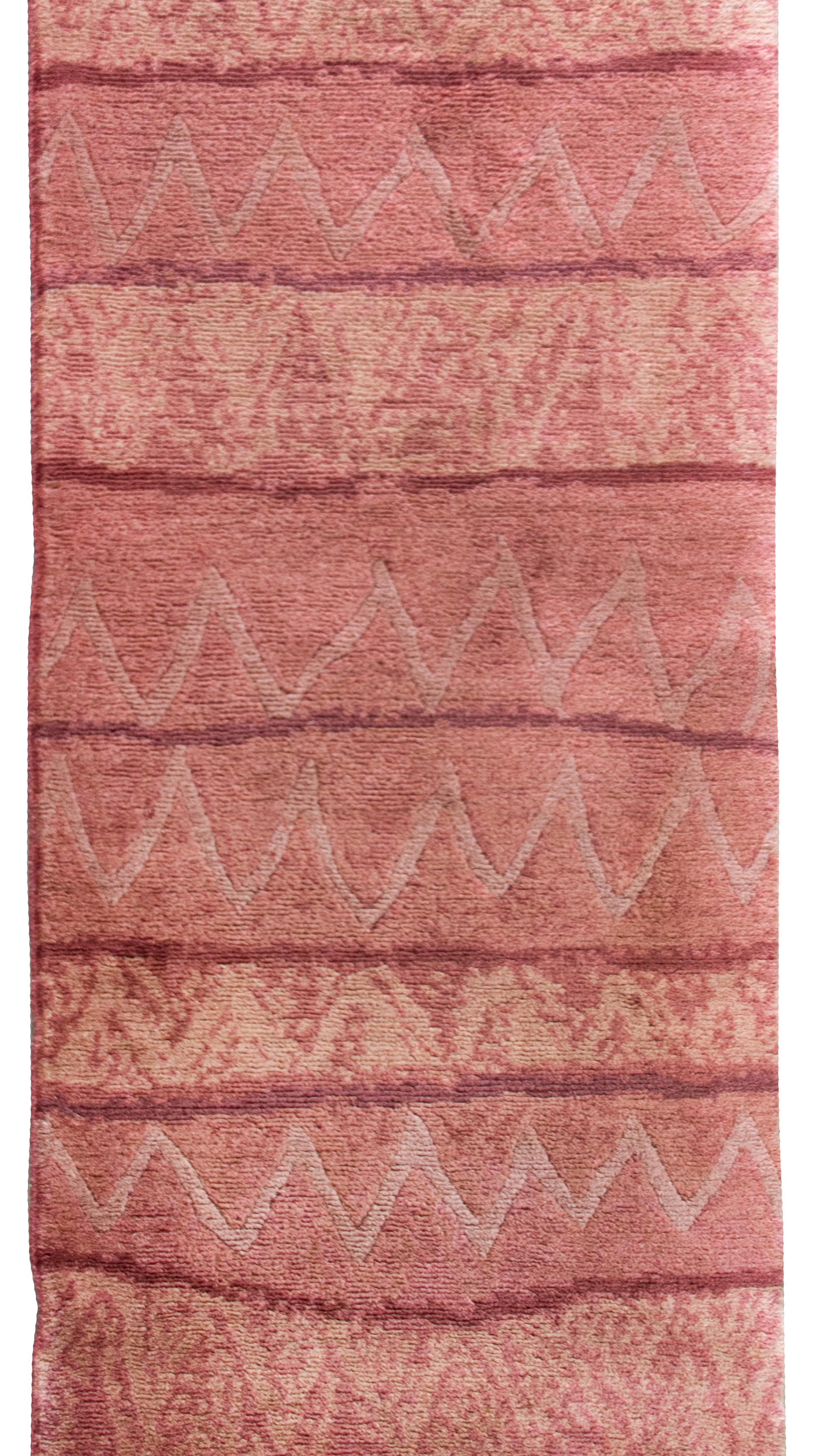 A vintage late 20th century Tibetan hand-knotted runner with a horizontal stripe pattern woven in varying shades of reds, and some stripes with zigzag patterns, and others with variegated colors.