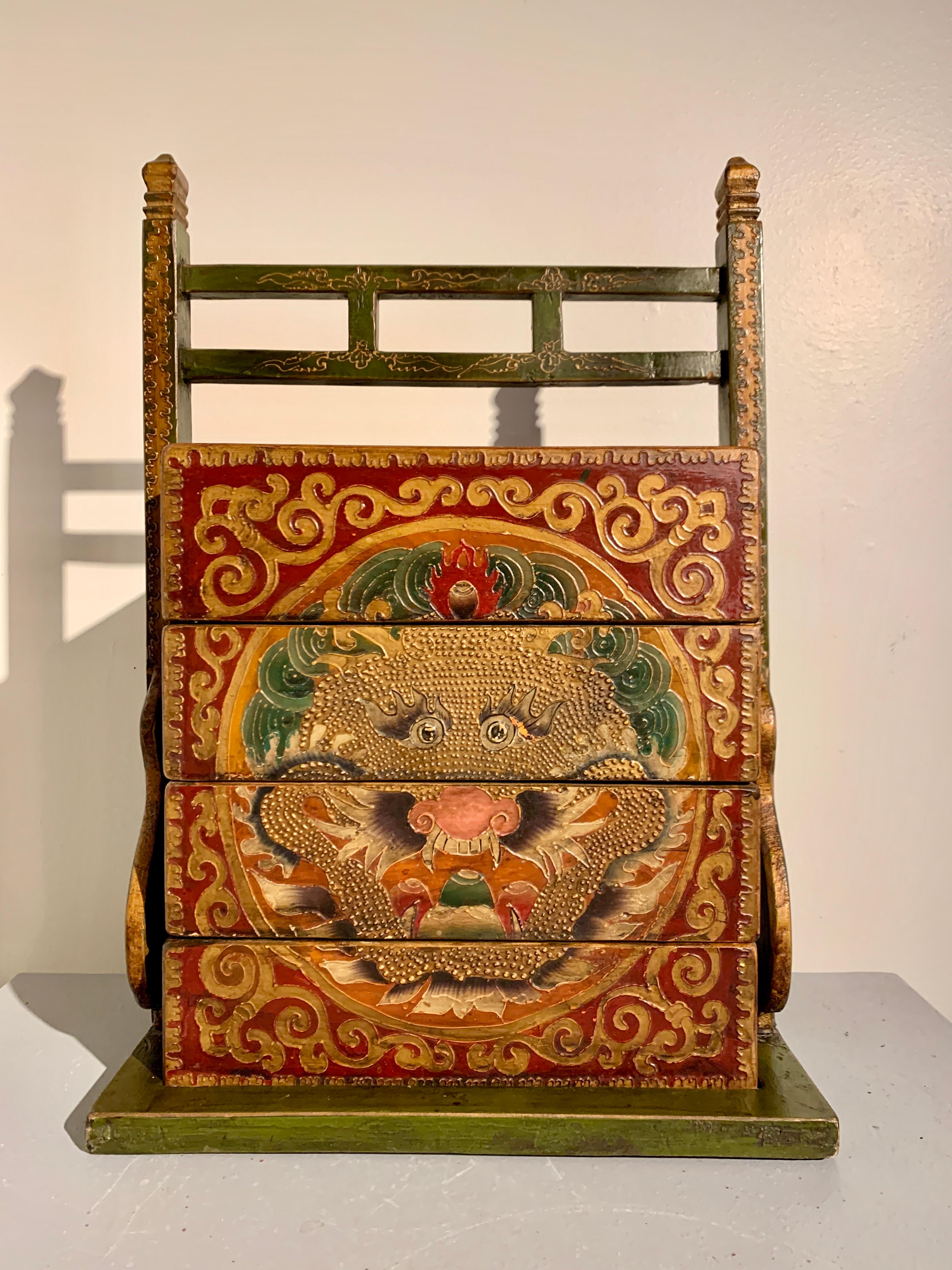 Eine hochdekorative chinesische, rot bemalte, stapelbare Picknickkiste und -träger, gemalt im tibetischen Stil, um 1990, China.

Die große bemalte und strukturierte Picknickkiste aus Holz besteht aus drei Schalen oder Boxen und einem Deckel, die
