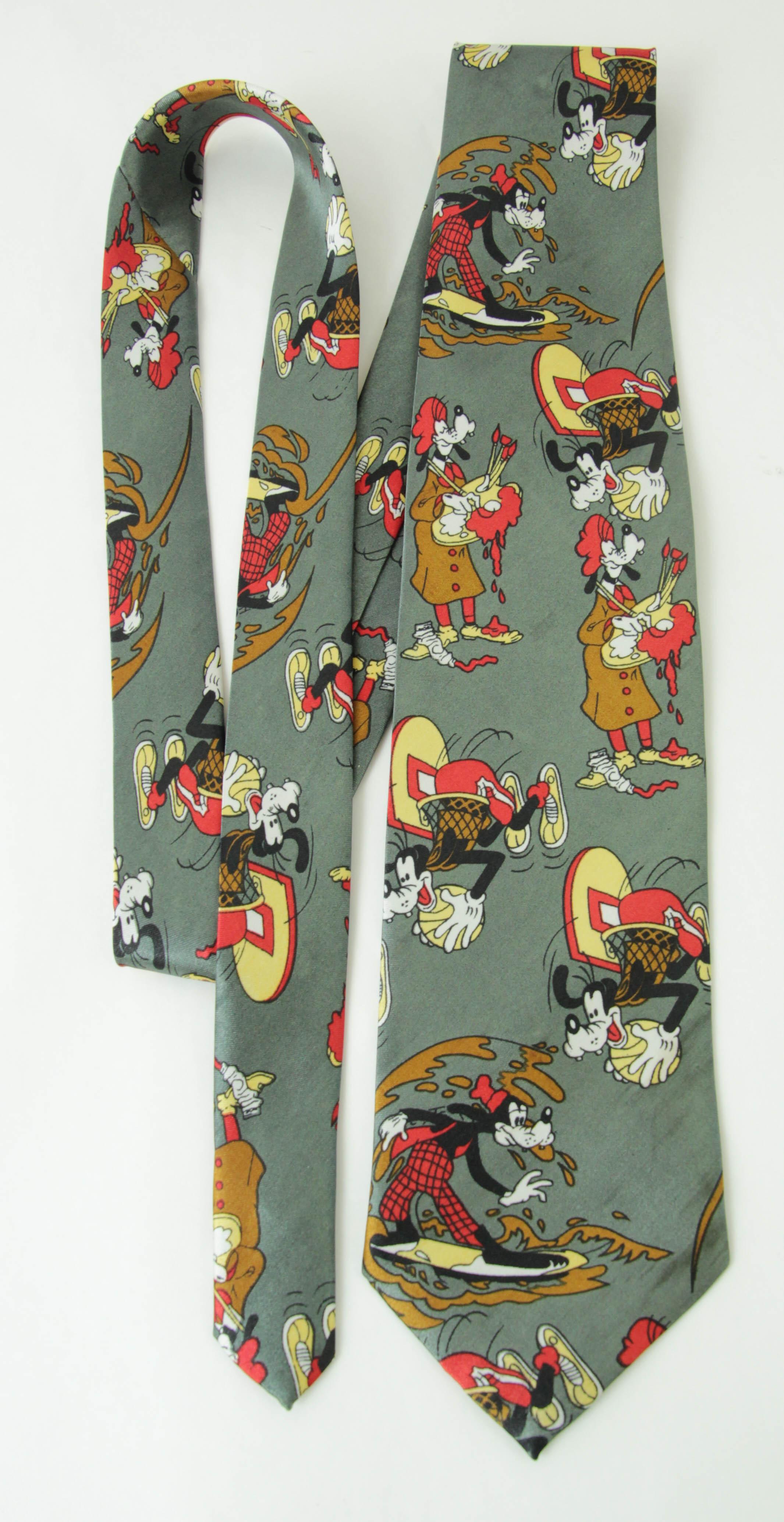 Vintage-Krawatte Walt Disney, Goofy, grüne Comics-Krawatte.
Mit dieser witzigen Krawatte, die Szenen von Goofy beim Surfen und Schwimmen zeigt, zeigst du, dass du Mickey Mouse liebst. 
Eine exklusive Kombination aus den Farben Grün, Braun, Rot und