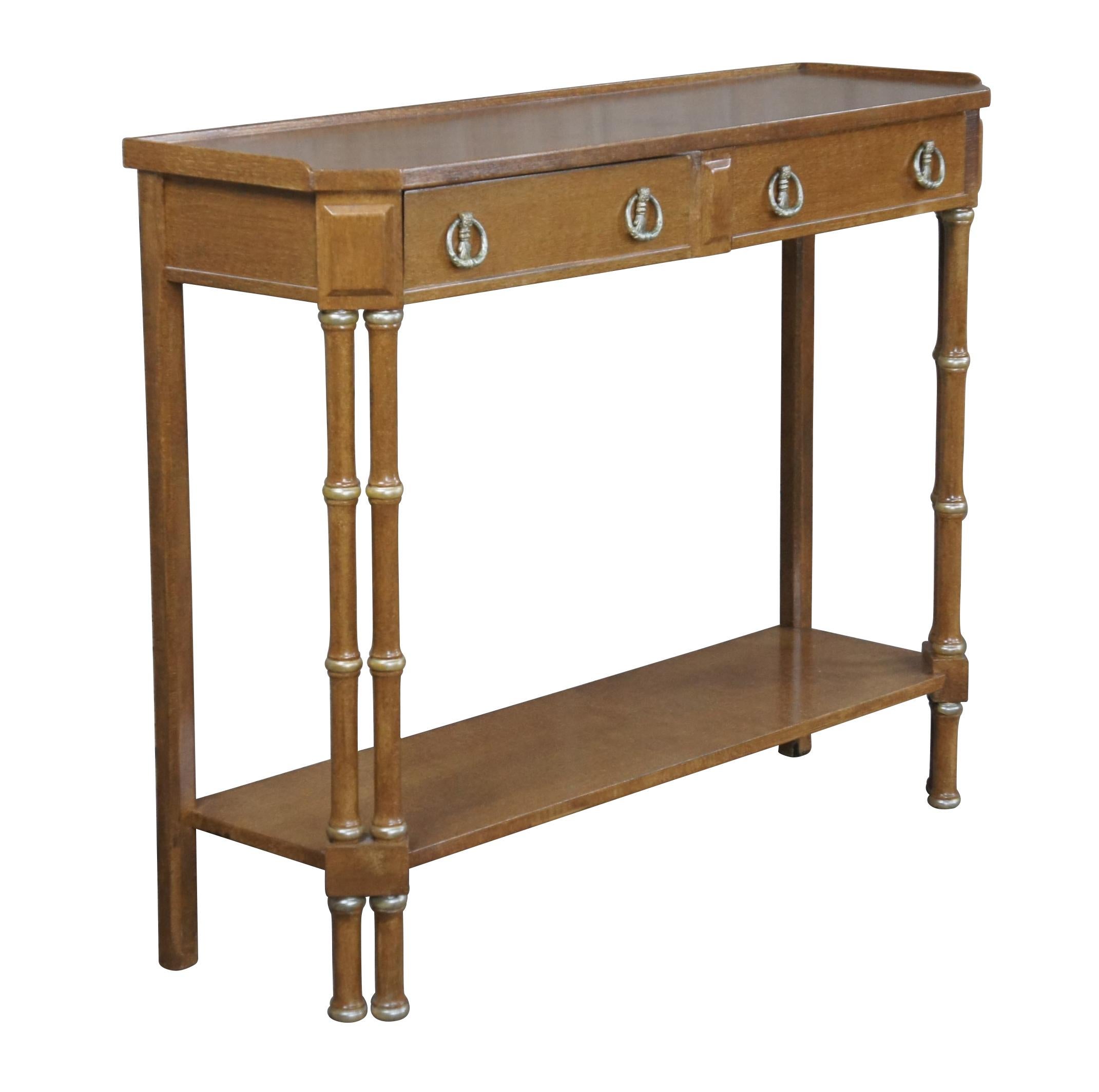 Vintage Campaign style tiered console or entry table featuring a slender profile with upper gallery over two drawers with Neoclassical brass hardware, supported by faux bamboo legs.

Dimensions:
36