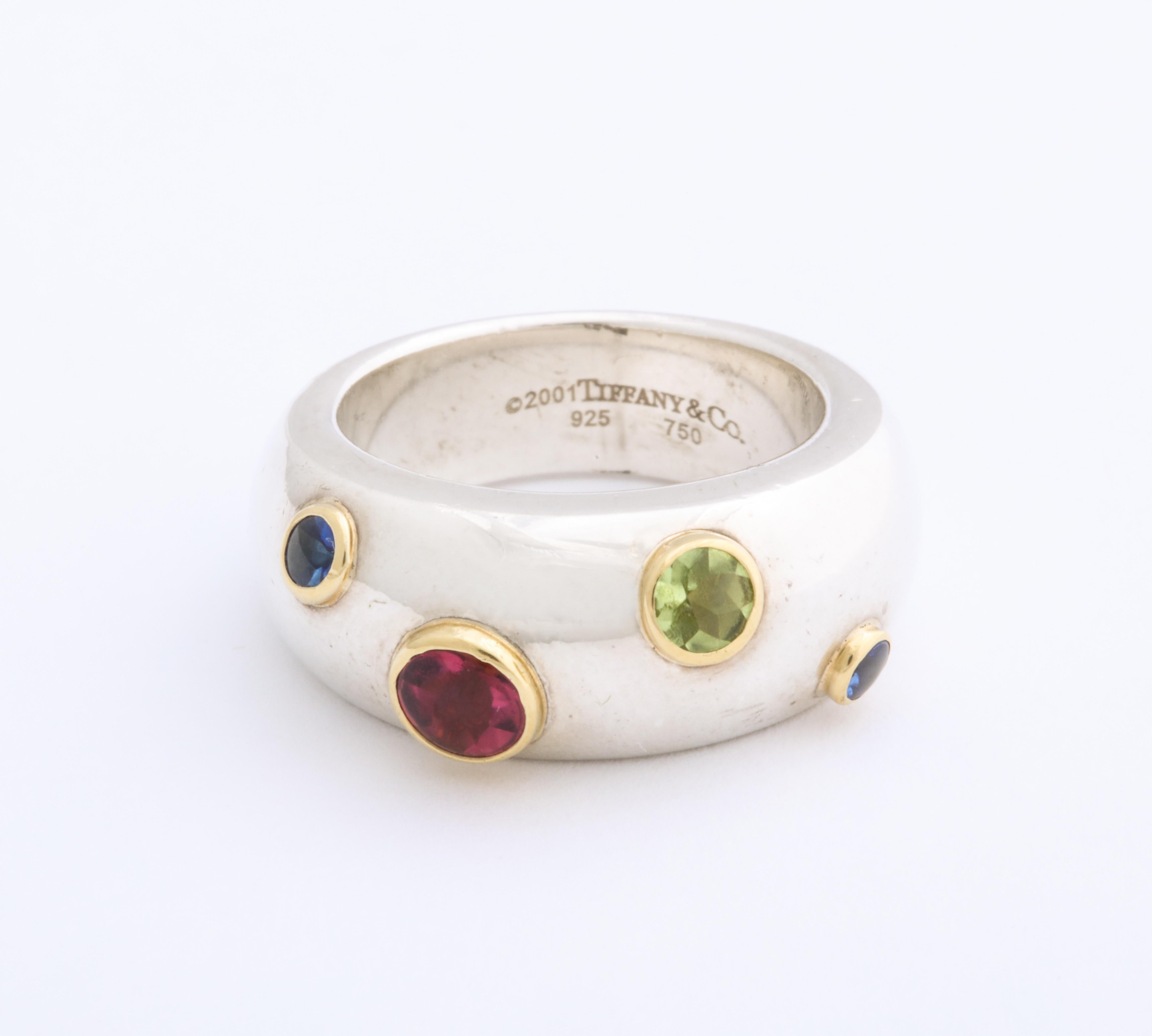 No longer in production, a significant Tiffany wedding or fashion ring sprinkles gold set sapphires, peridot and pink tourmaline in a serpentine river around your finger. The gems are standout with beautiful Tiffany quality with yellow gold bezels