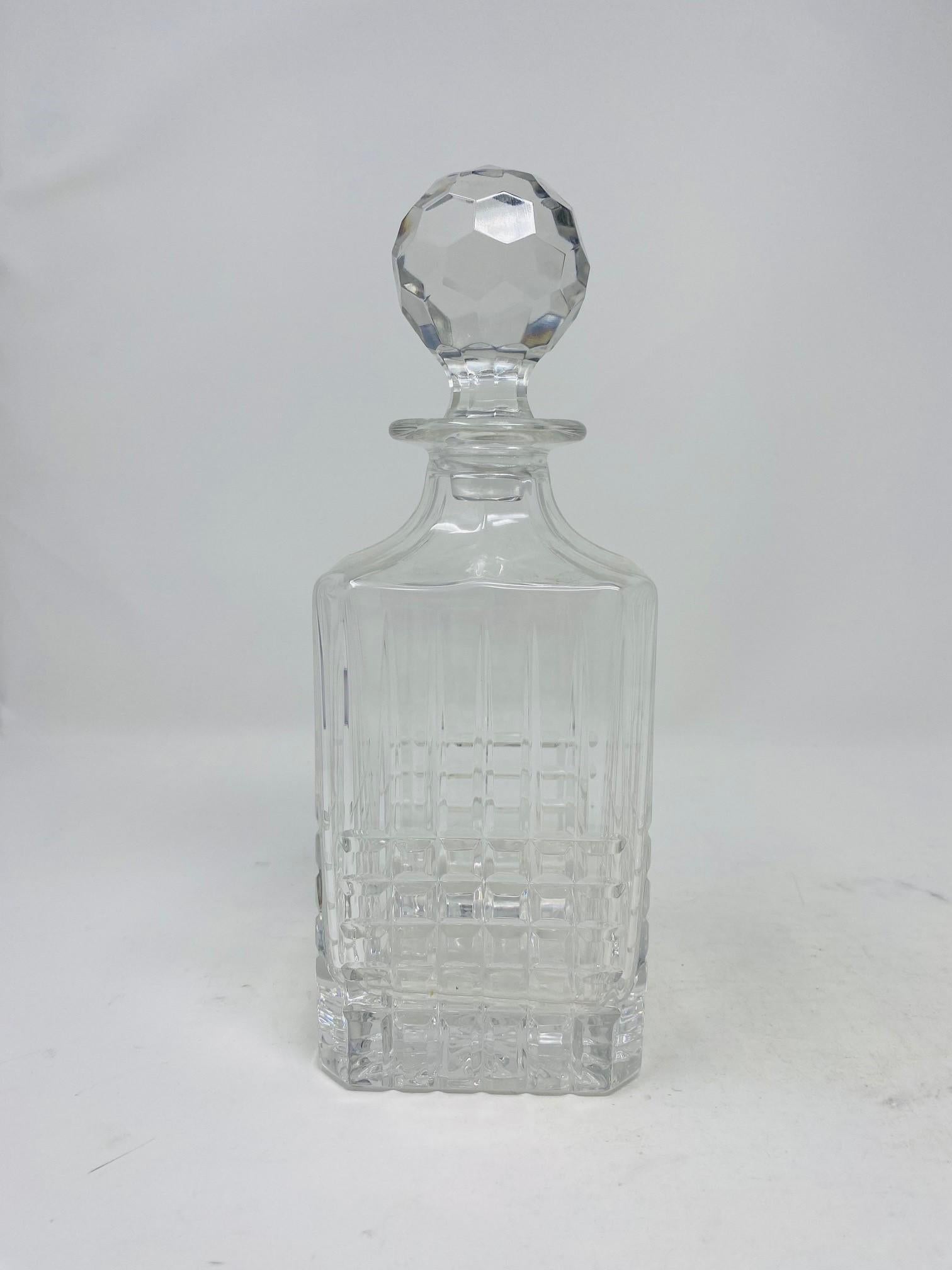 A crystal beauty, this whiskey decanter by Tiffany and Co. Features a vertical arching lines on top of cubic cuts garnishing the lower half of the decanter. Finished with a spherical, faceted stopper. Marked: 
