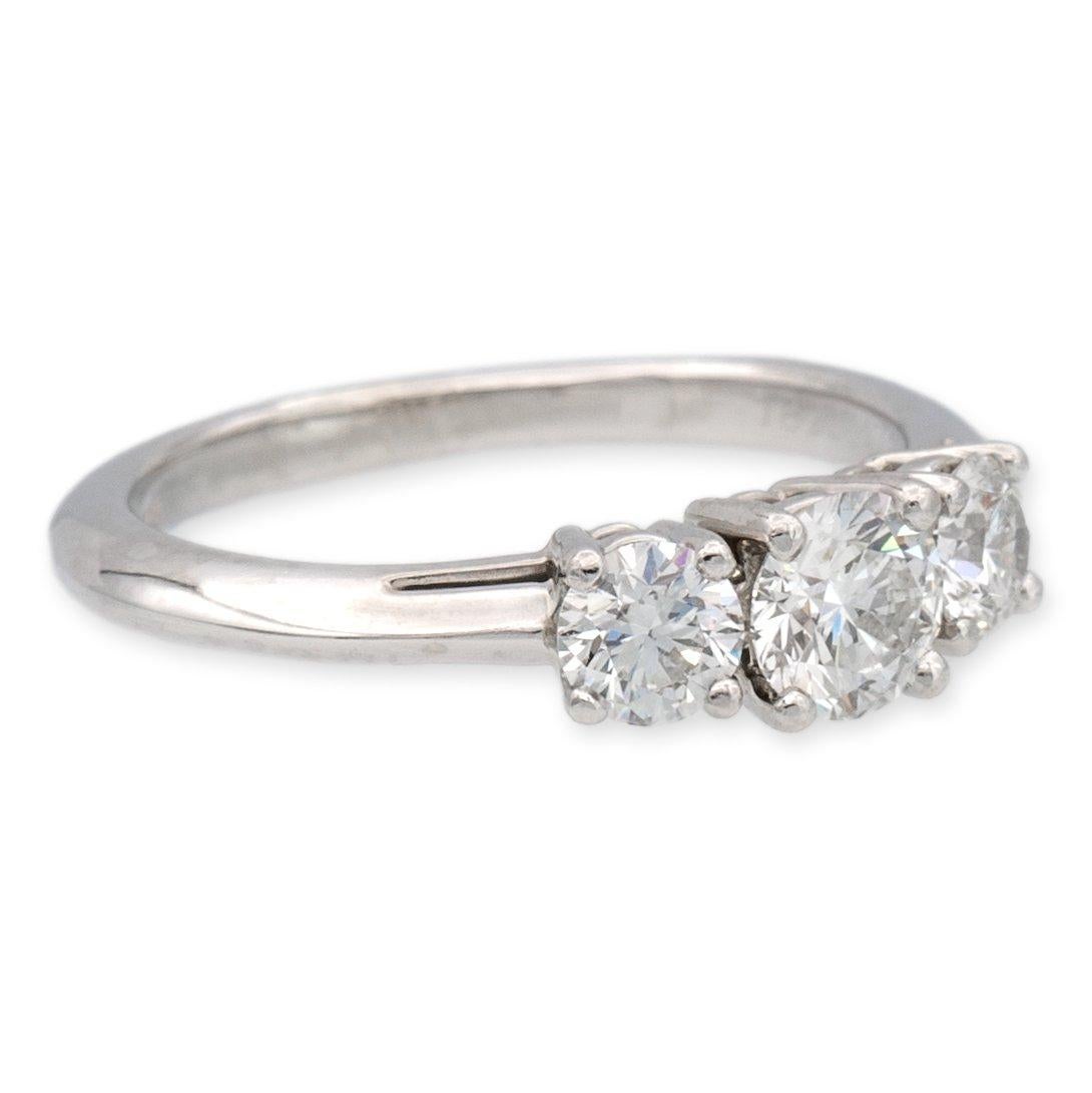 Vintage Tiffany & Co. classic three stone engagement ring finely crafted in platinum featuring round brilliant cut diamond stones in an open gallery design. The center diamond weighs 0.41 carats F-G color, VVS1-VVS2 clarity and two side diamonds