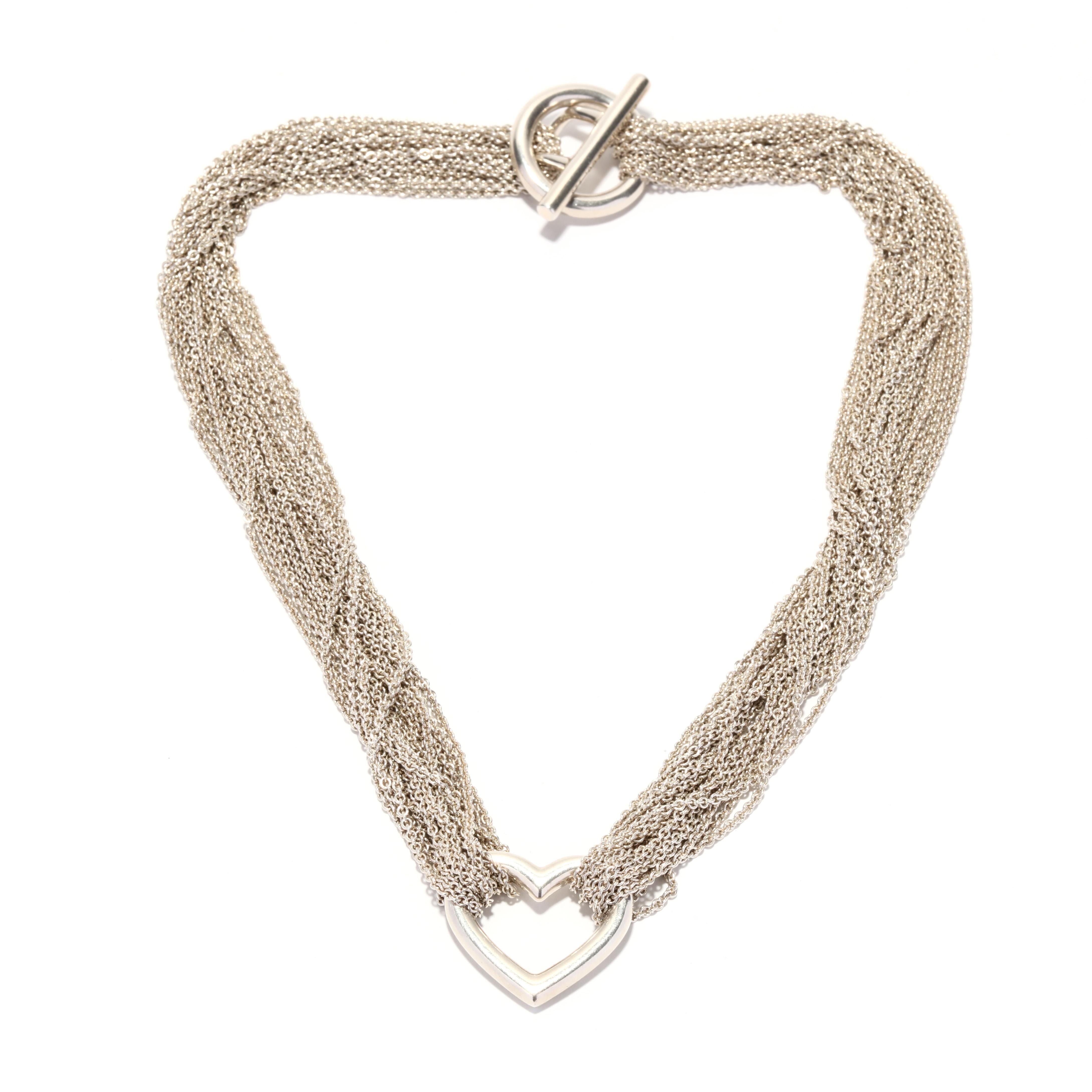 A vintage Tiffany and Company sterling silver heart necklace. This classic style necklace features twenty strands of silver cable chain connected in the center with an open heart motif and with an oversize toggle clasp. This necklace is accompanied